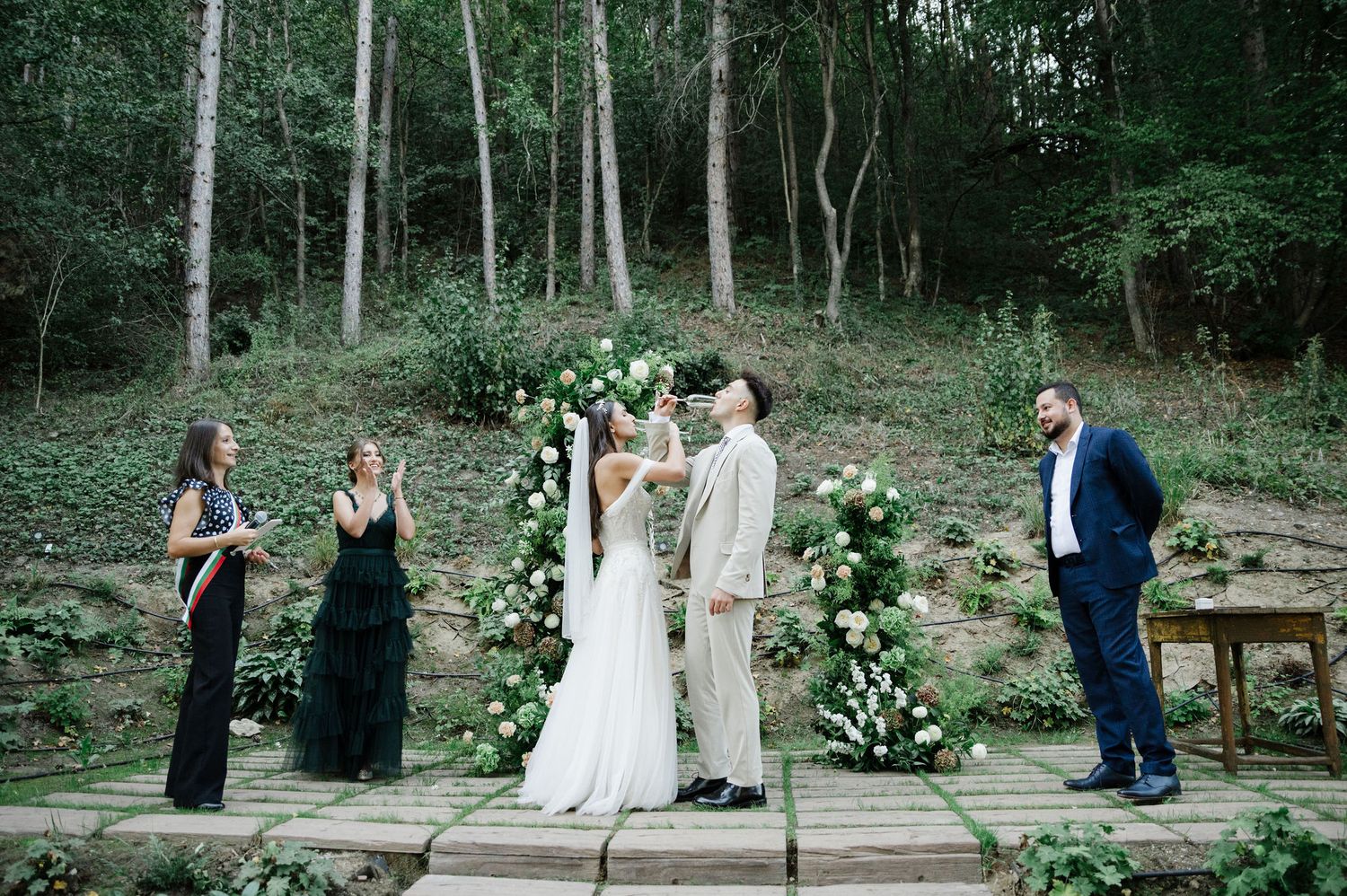 Intimate forest wedding with stone staircase and elegant white flower arrangements.
