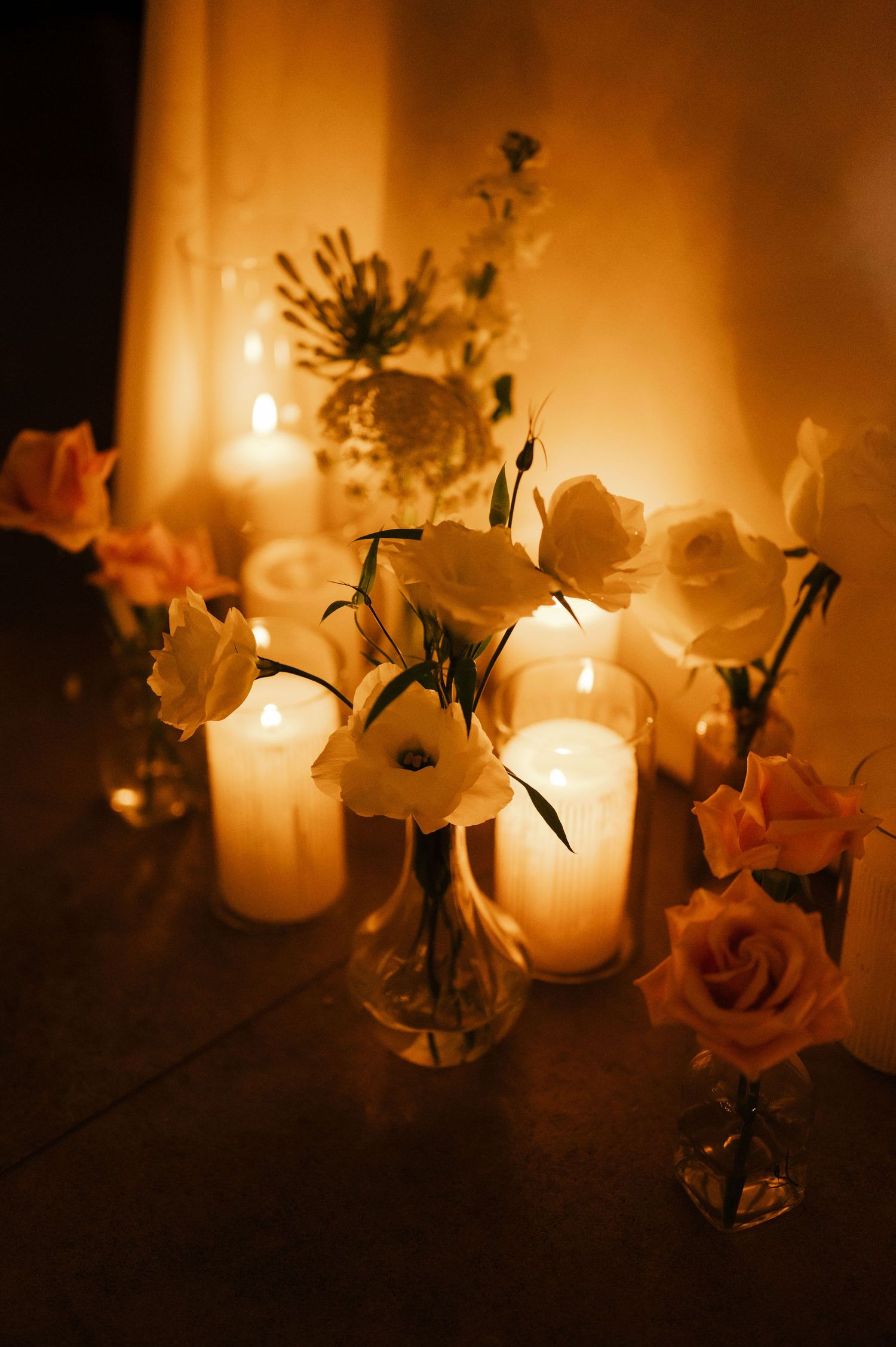 Romantic candlelit table settings with delicate white flowers in glass vases.