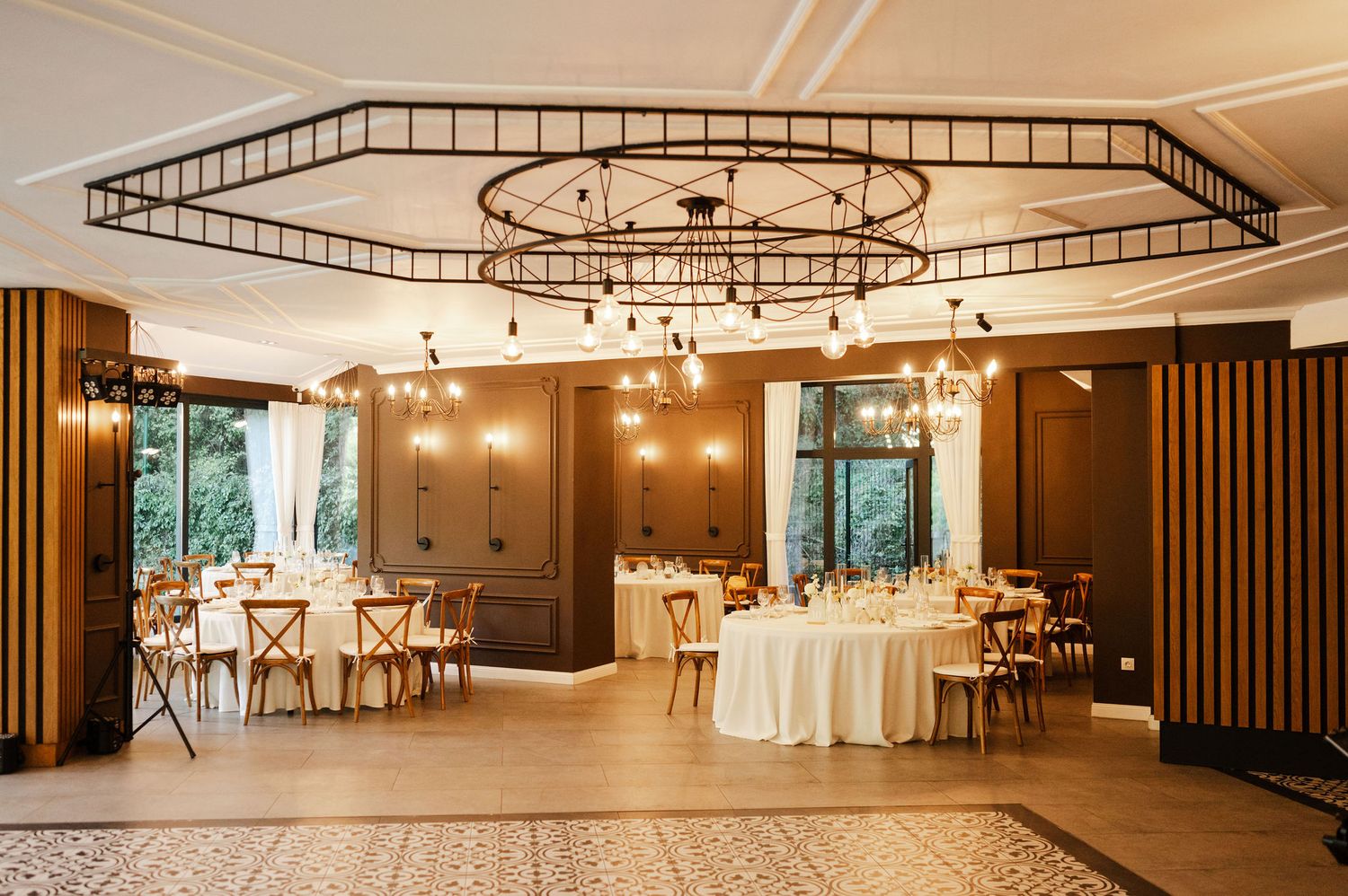 Contemporary event space with industrial ceiling details, chandeliers and warm wood accents.