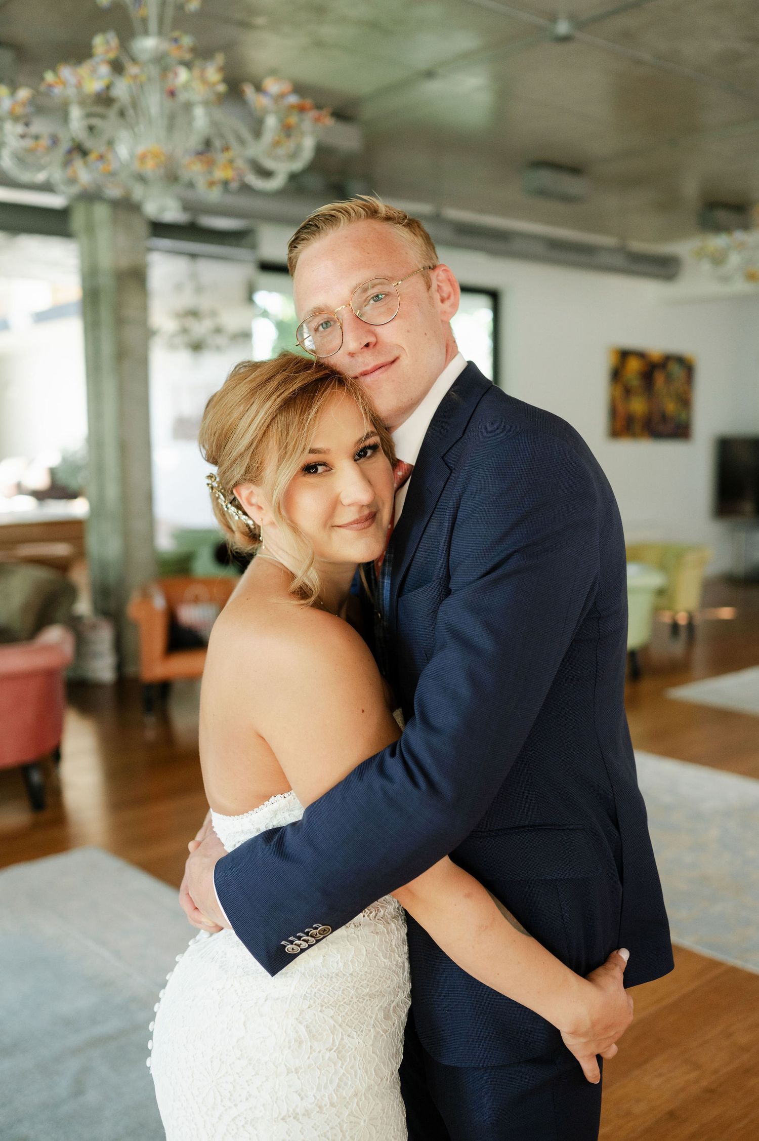 Joyful wedding couple embracing during their first look in bright indoor setting.