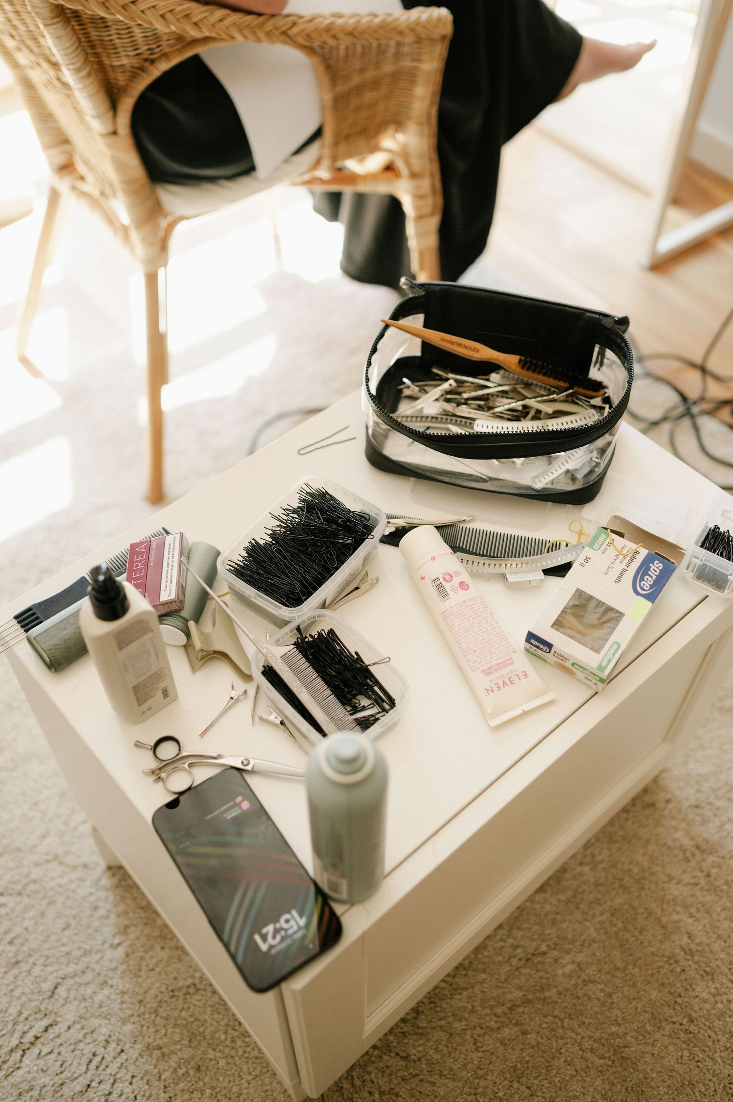 Makeup brushes, tools and beauty products arranged on white surface in natural lighting.