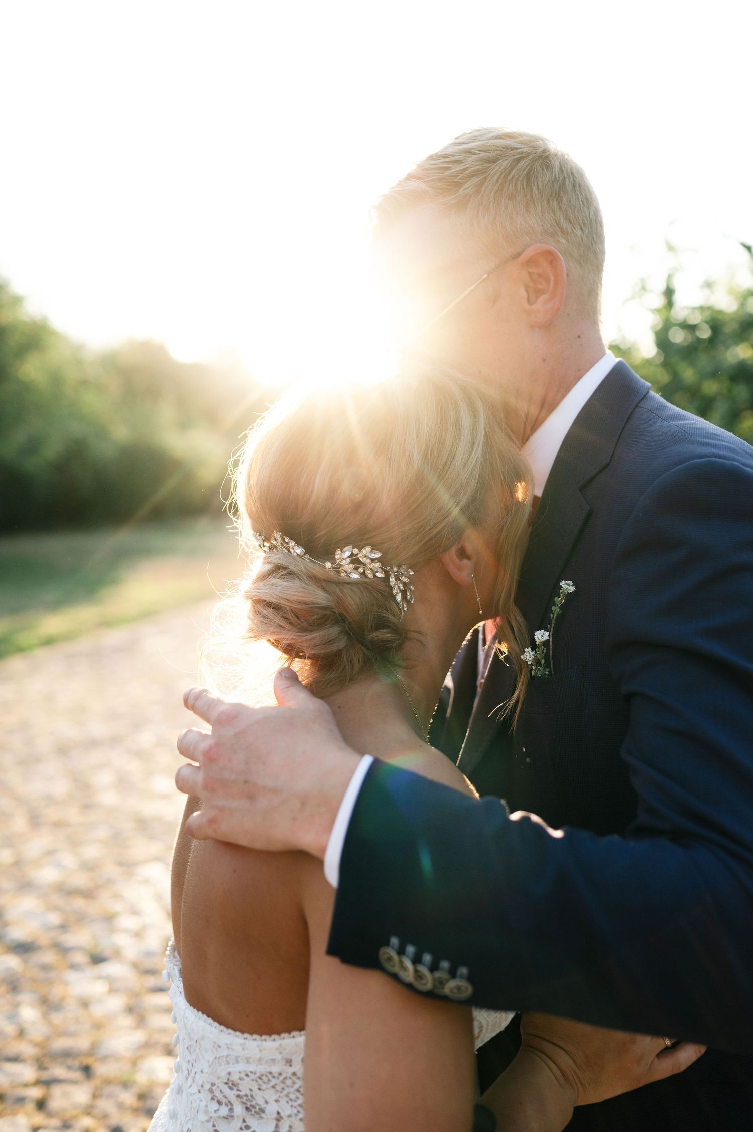 Intimate wedding couple embracing during golden hour photoshoot on cobblestone path.