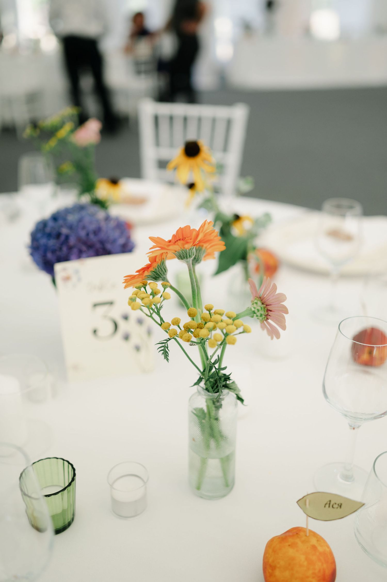 Wedding reception table decorated with rustic mason jars, fresh flowers, and citrus accents.