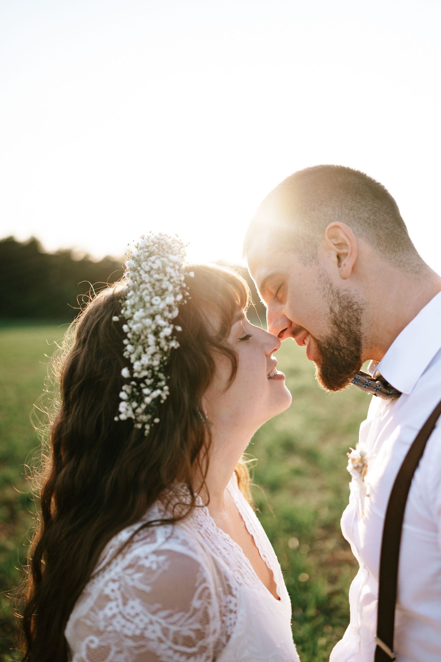 Sunlit wedding portrait capturing romantic moment between couple in rustic outdoor setting.