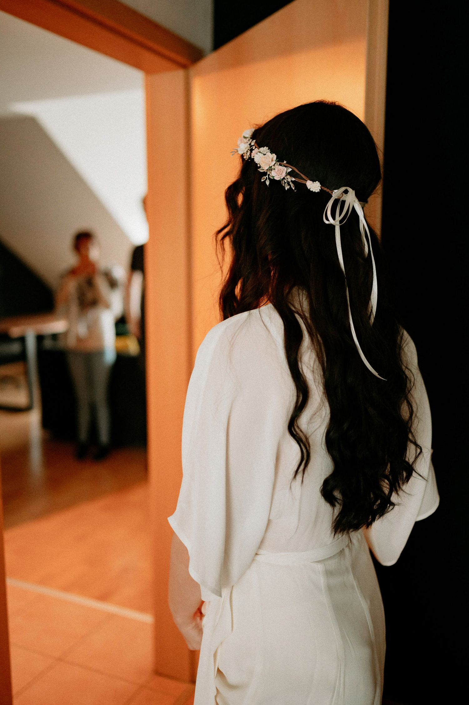 Person in white dress photographed from behind in warm-toned indoor lighting.