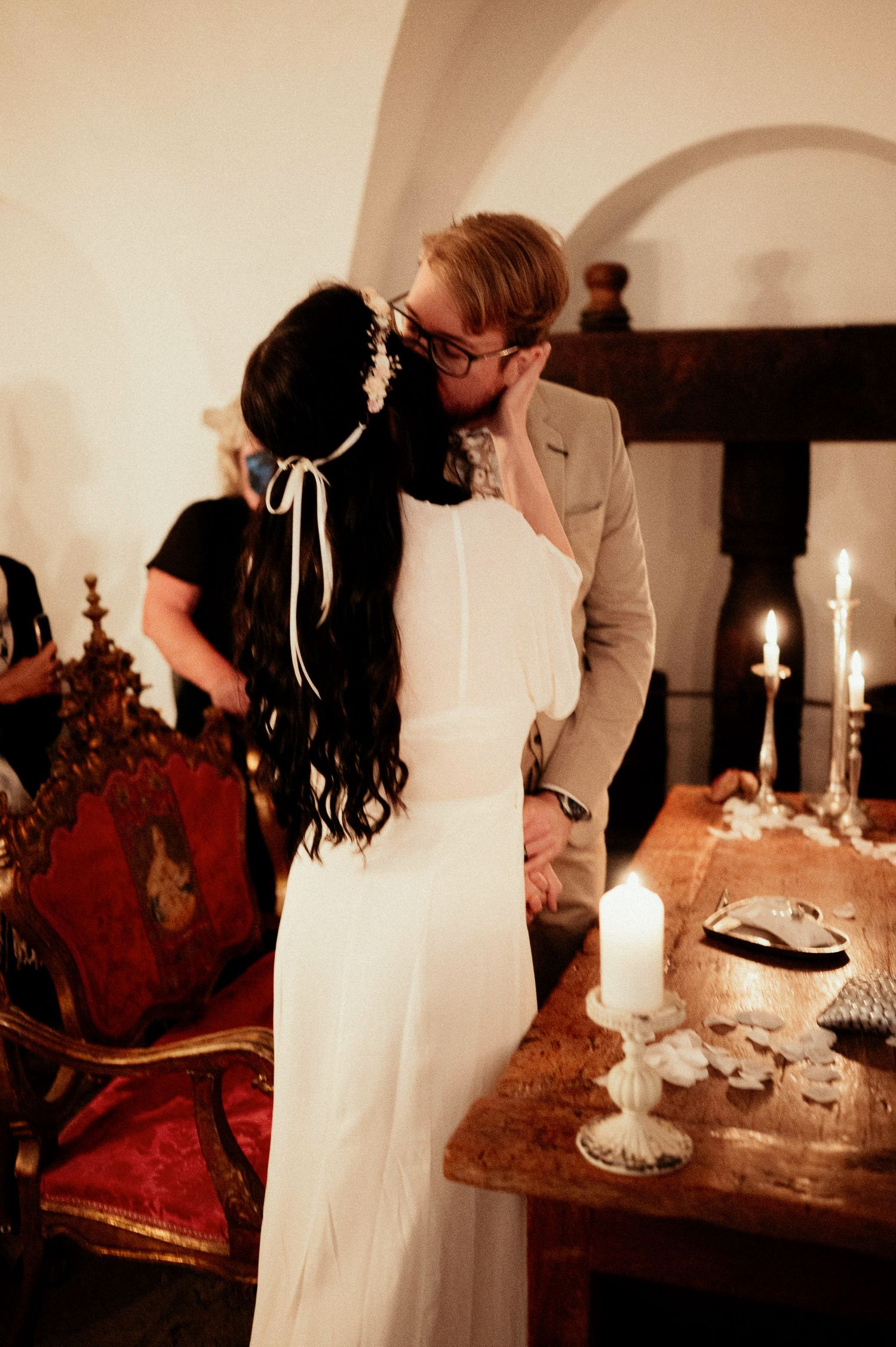 Candlelit ceremony moment with couple near vintage wooden table.