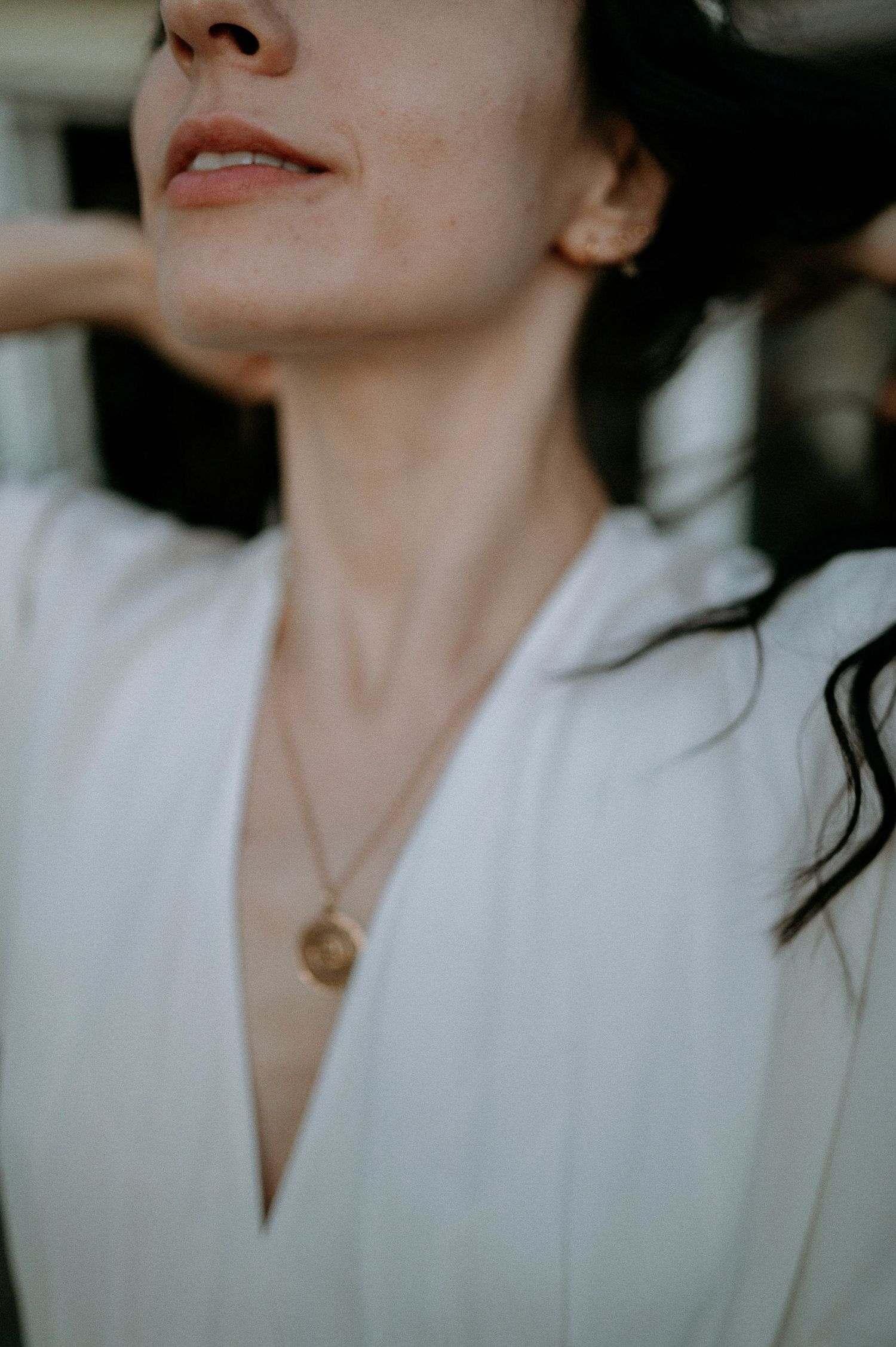 Close-up portrait showing delicate necklace and white collar detail.