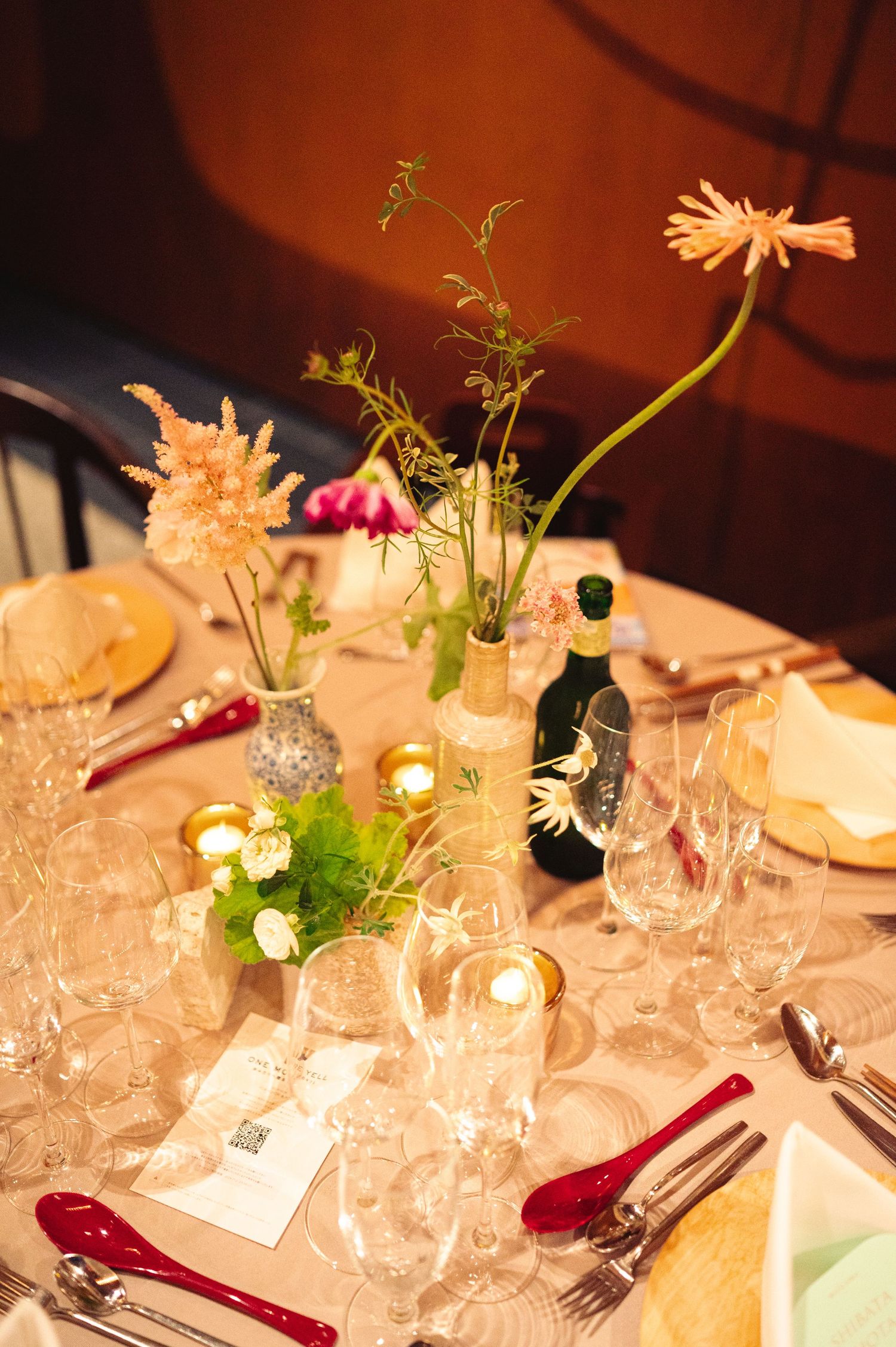 Elegant table decorations featuring crystal glasses and fresh flower arrangements in soft lighting.