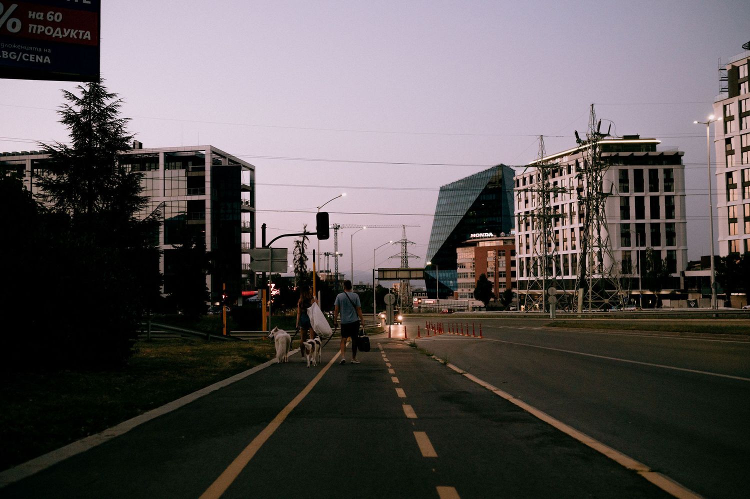 Urban street scene at dusk showing modern apartment buildings and empty road.