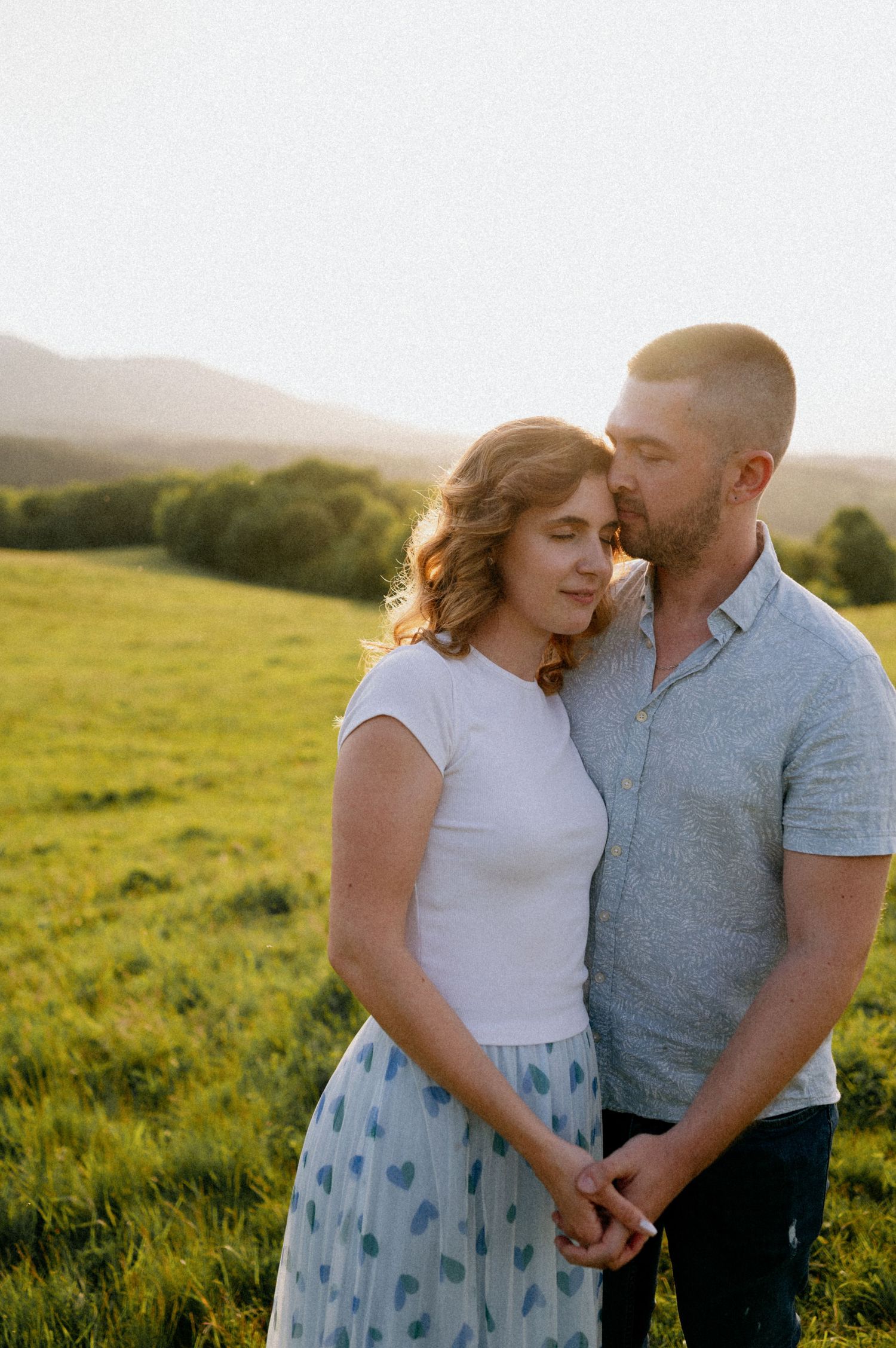 A couple shares a sweet moment together in a sun-soaked field.