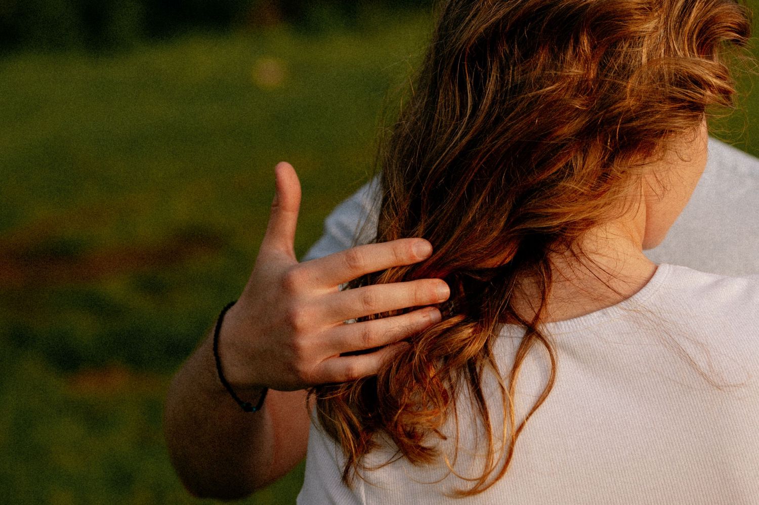 Sunlit curls of hair being gently touched in warm evening light.