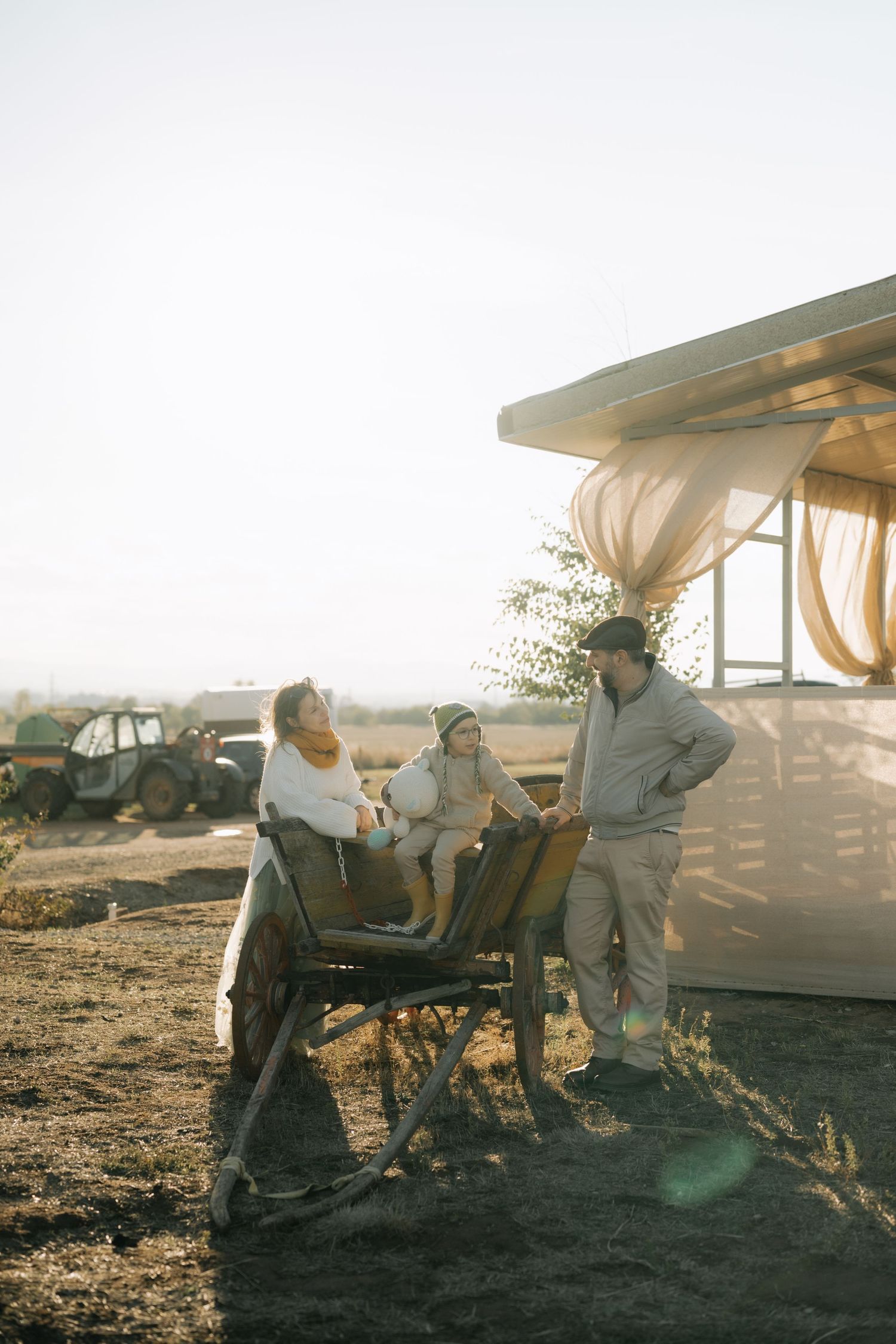 Couple relaxing in lounge chairs at sunset on a beach with warm golden light filtering through canvas awnings.