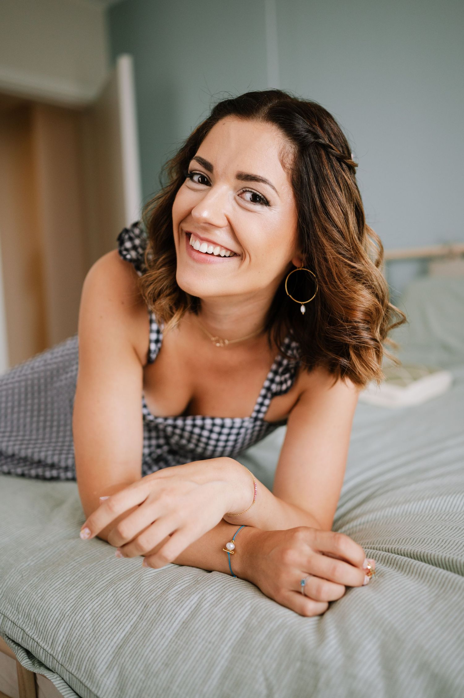 Lifestyle portrait series showing relaxed poses on gray bedding while wearing a checkered top.