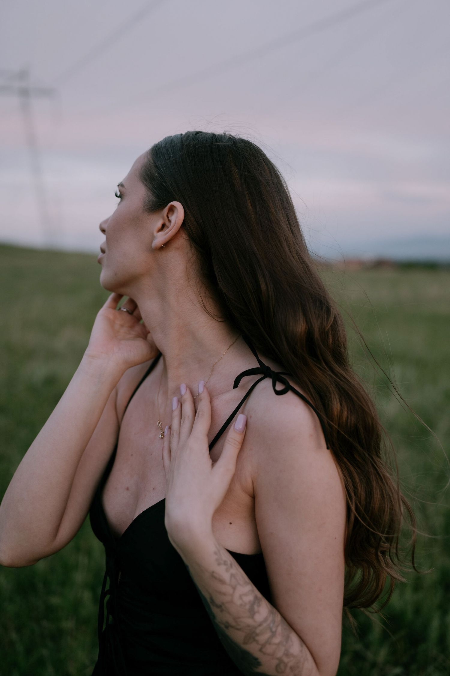 A series of artistic photos showing someone with long dark hair in a black top against a moody outdoor landscape.