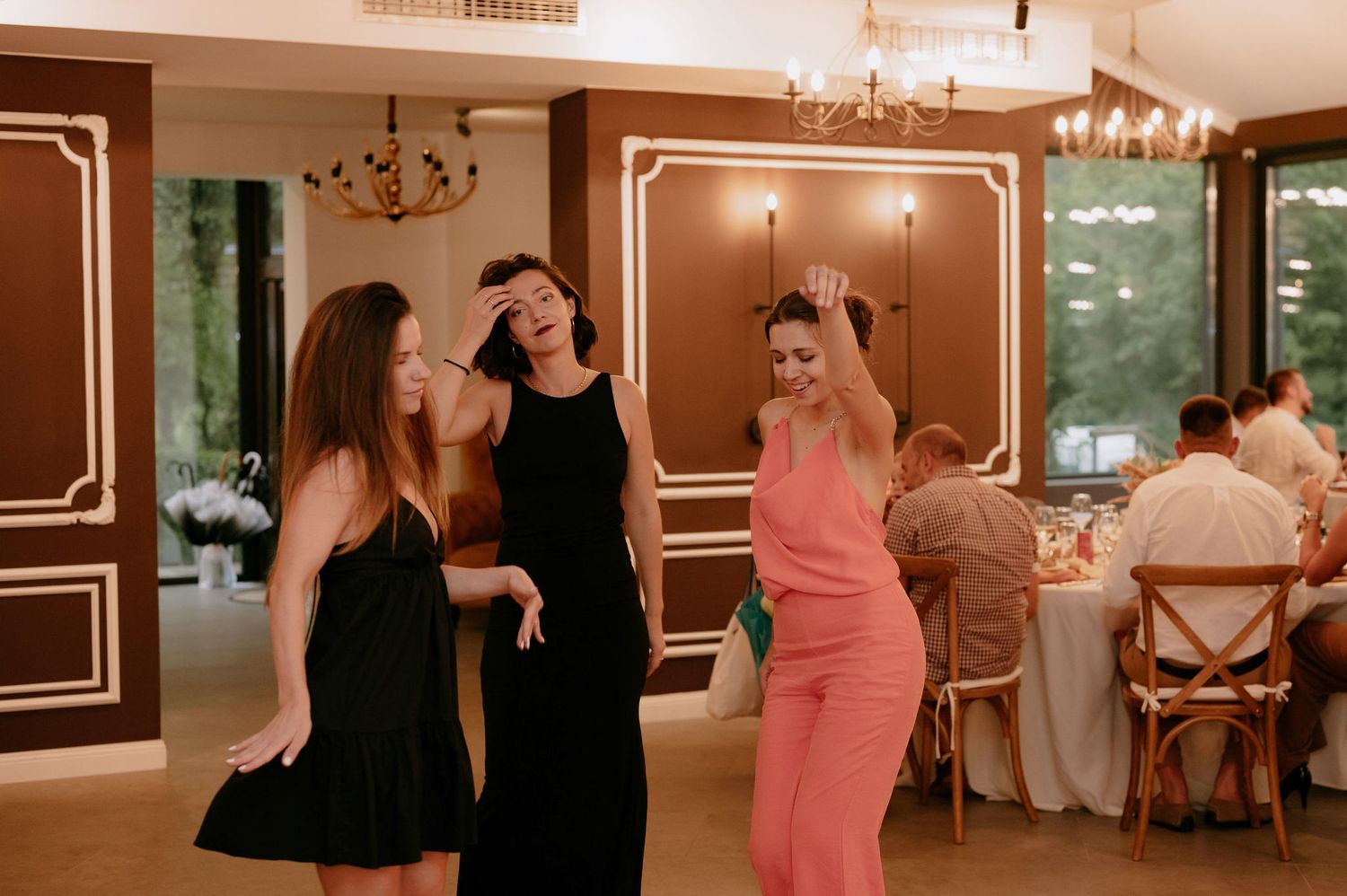 People dancing together at an elegant indoor event with warm lighting and decorative wall panels.