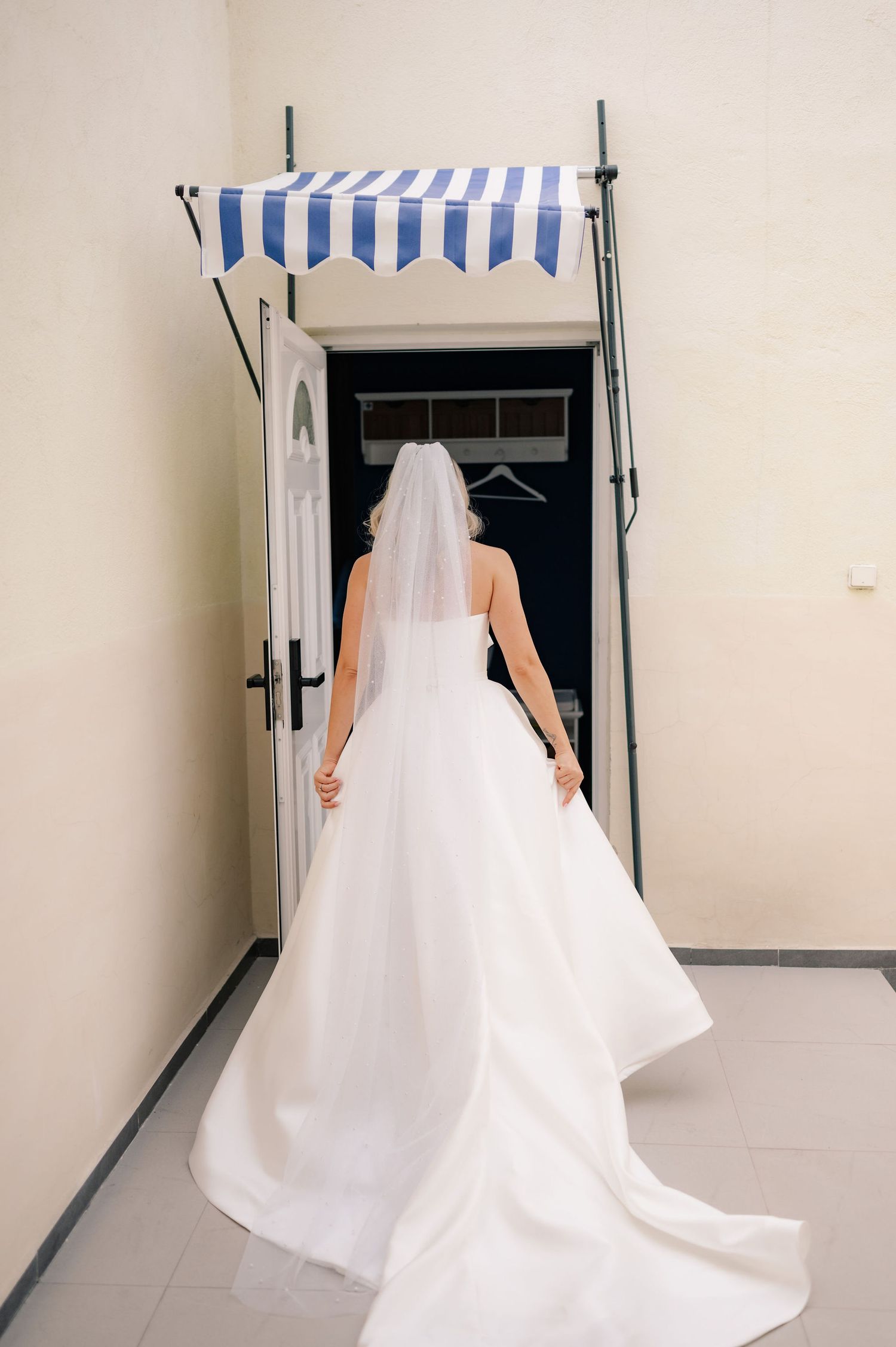 A series of photos showing the back of a wedding dress with a flowing white train as the wearer walks through a doorway.