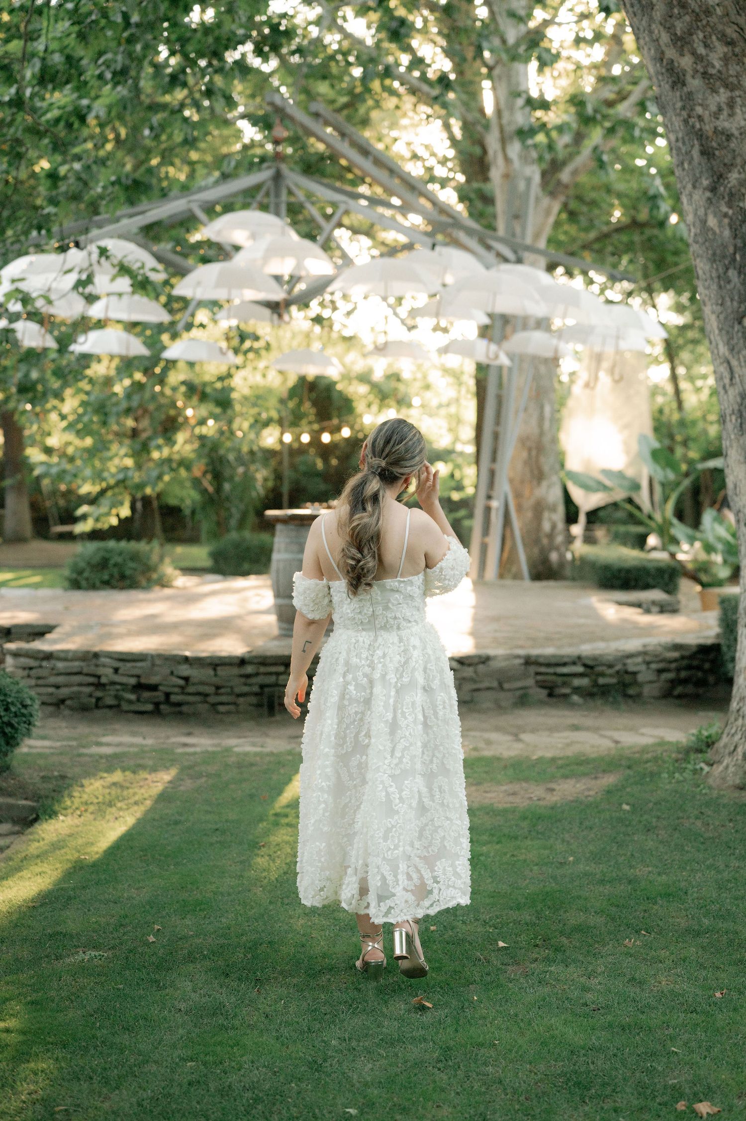 Two children in white dresses twirl and dance together on a sunlit lawn during a summer celebration.