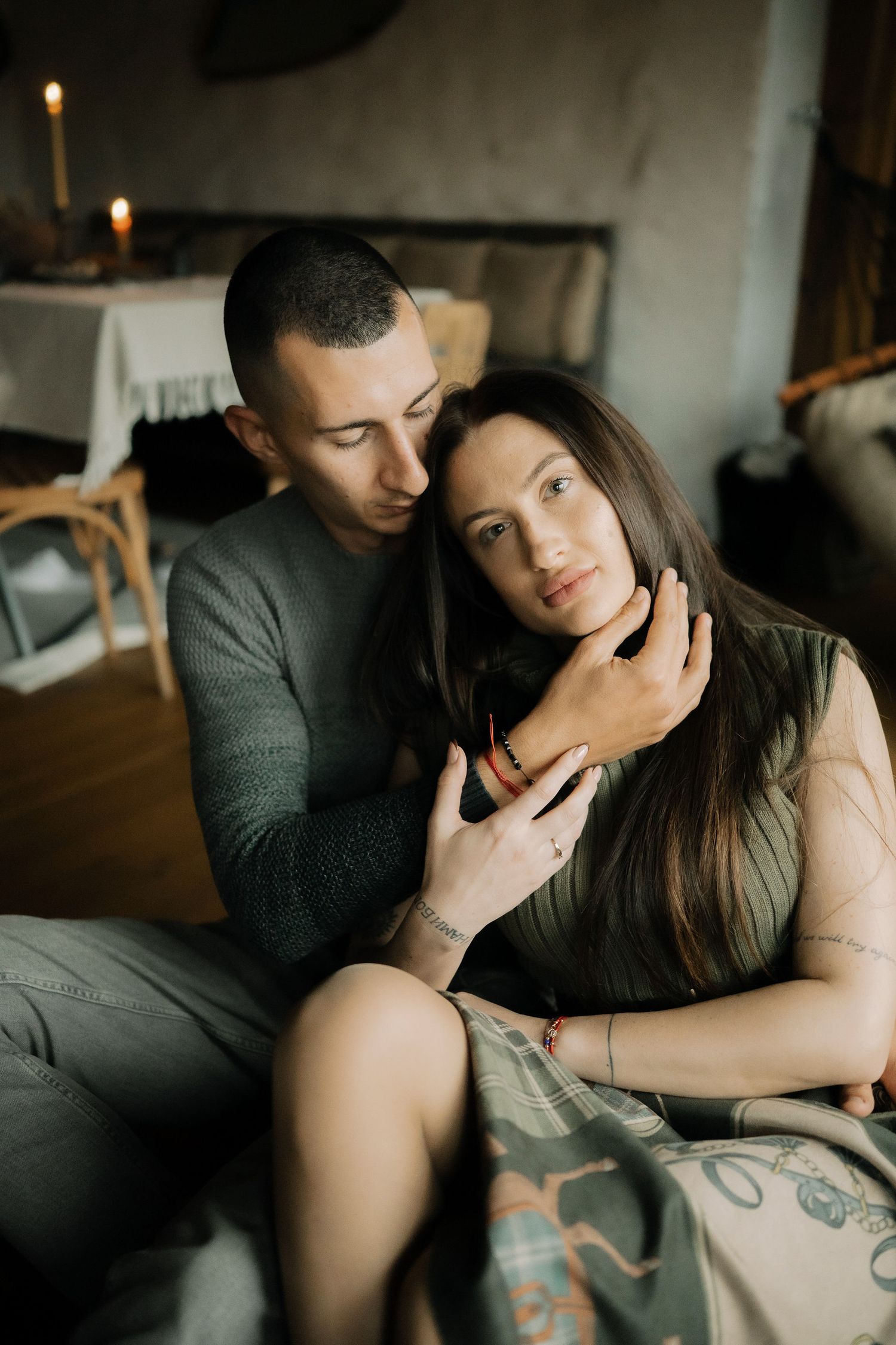 Couple sharing intimate moments on a couch in atmospheric natural lighting.