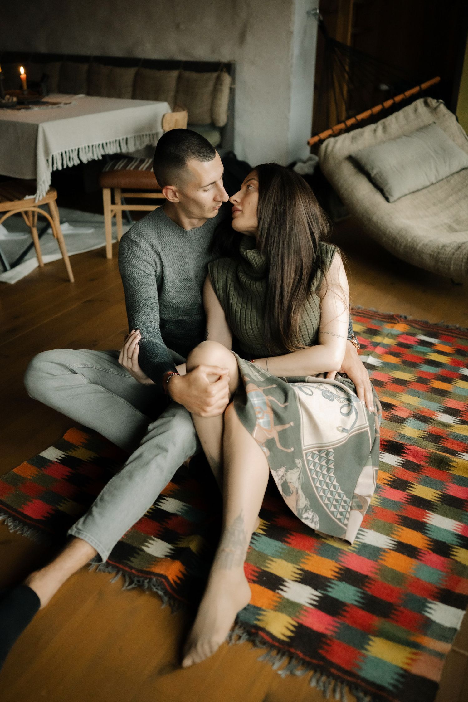 A couple relaxes together on a colorful patterned rug in a cozy living room setting.