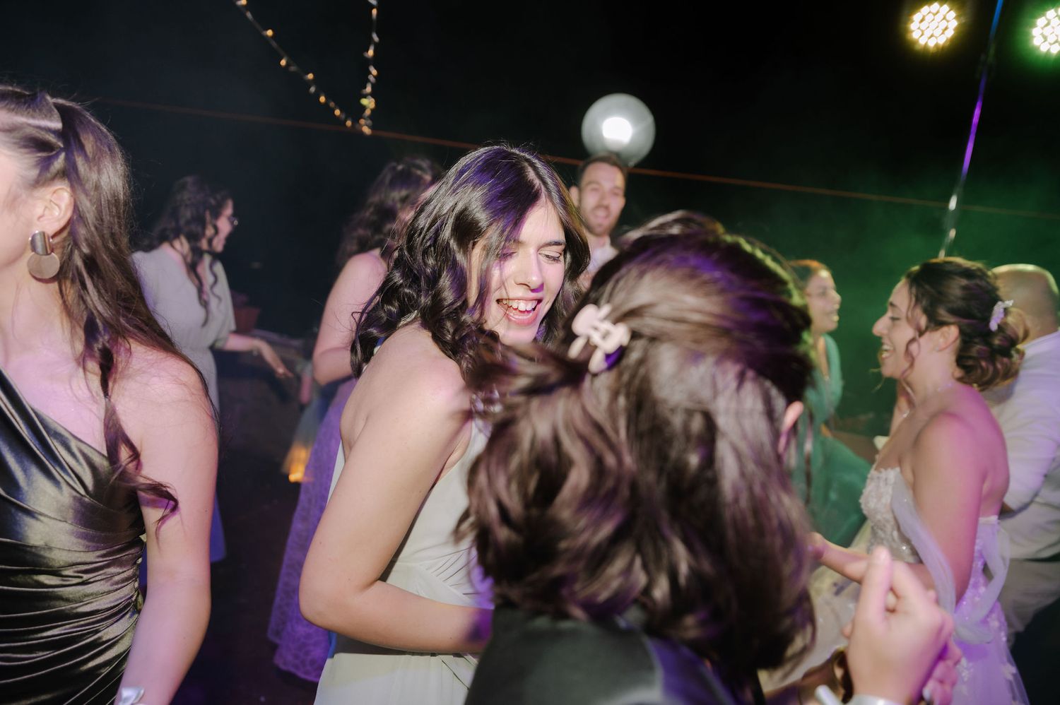 People dancing together at a nightclub with colorful lights in the background.