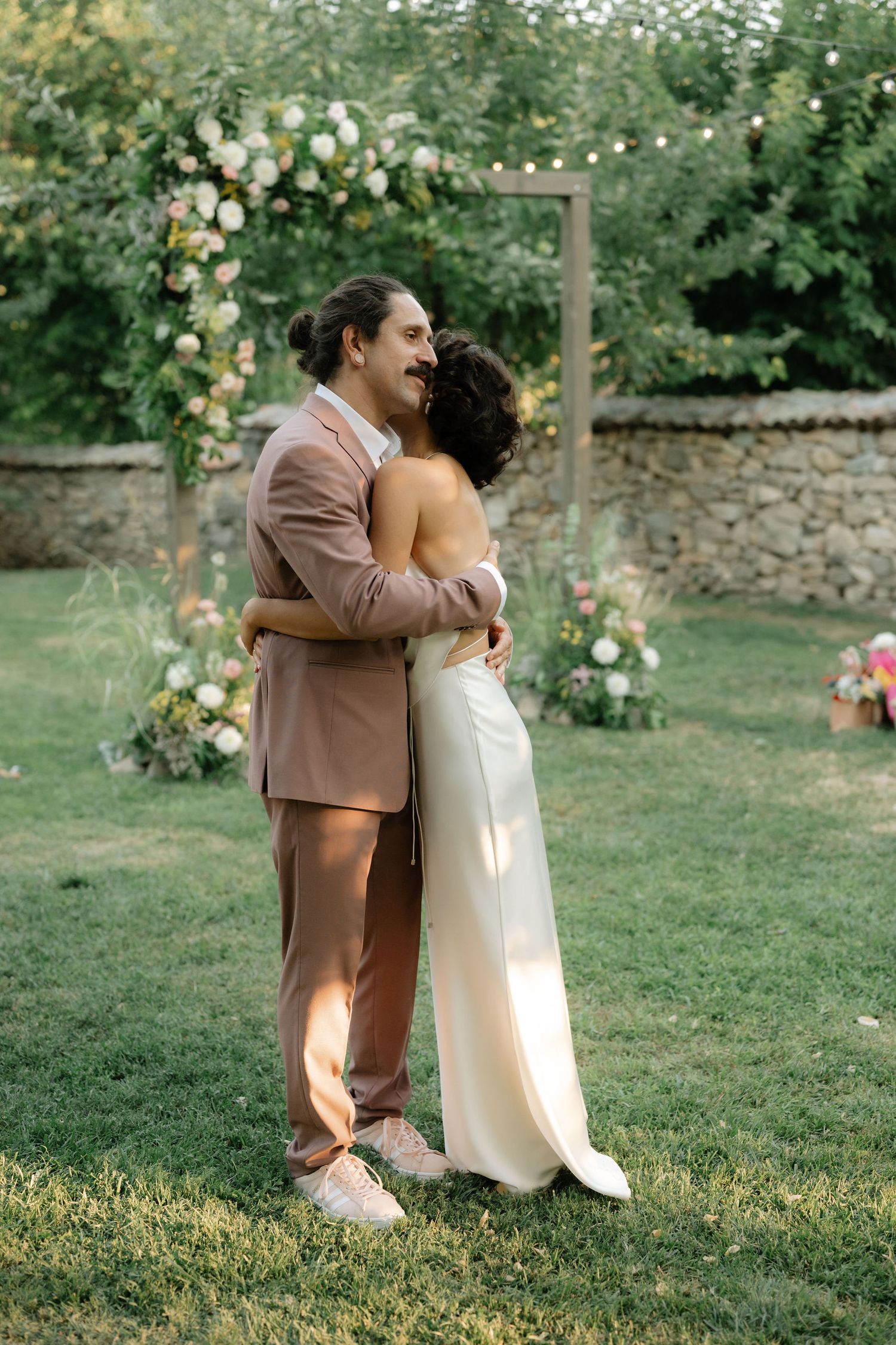 A couple shares a romantic moment in a garden filled with blooming roses on their wedding day.