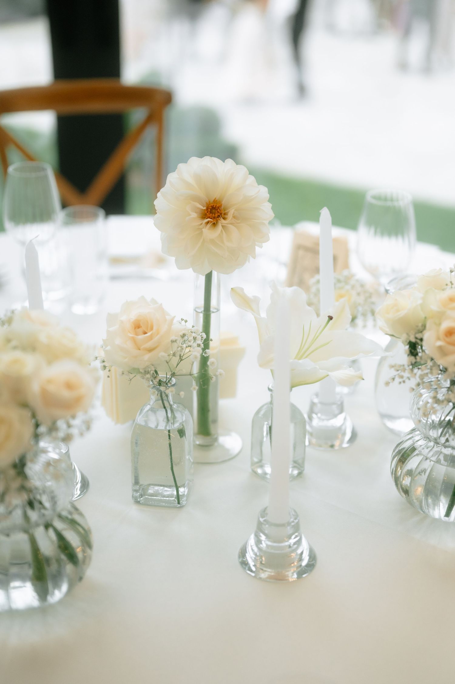 White dahlias and roses in glass vases create an elegant table centerpiece at a wedding reception.