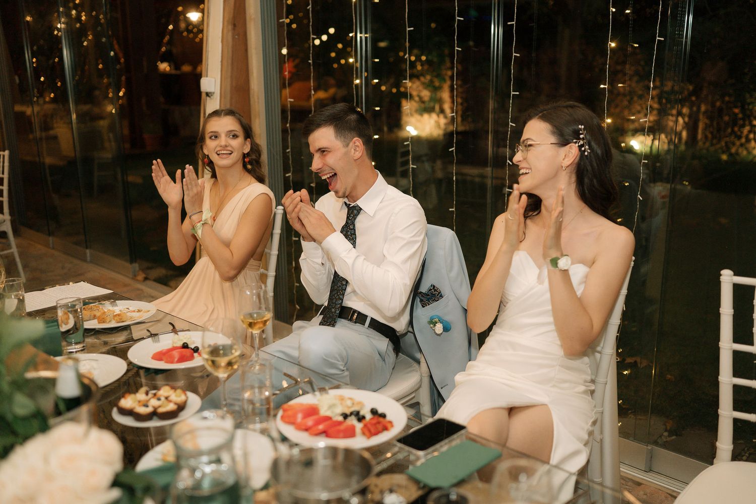 Group of people enjoying dinner and conversation at an elegant restaurant table in evening setting.