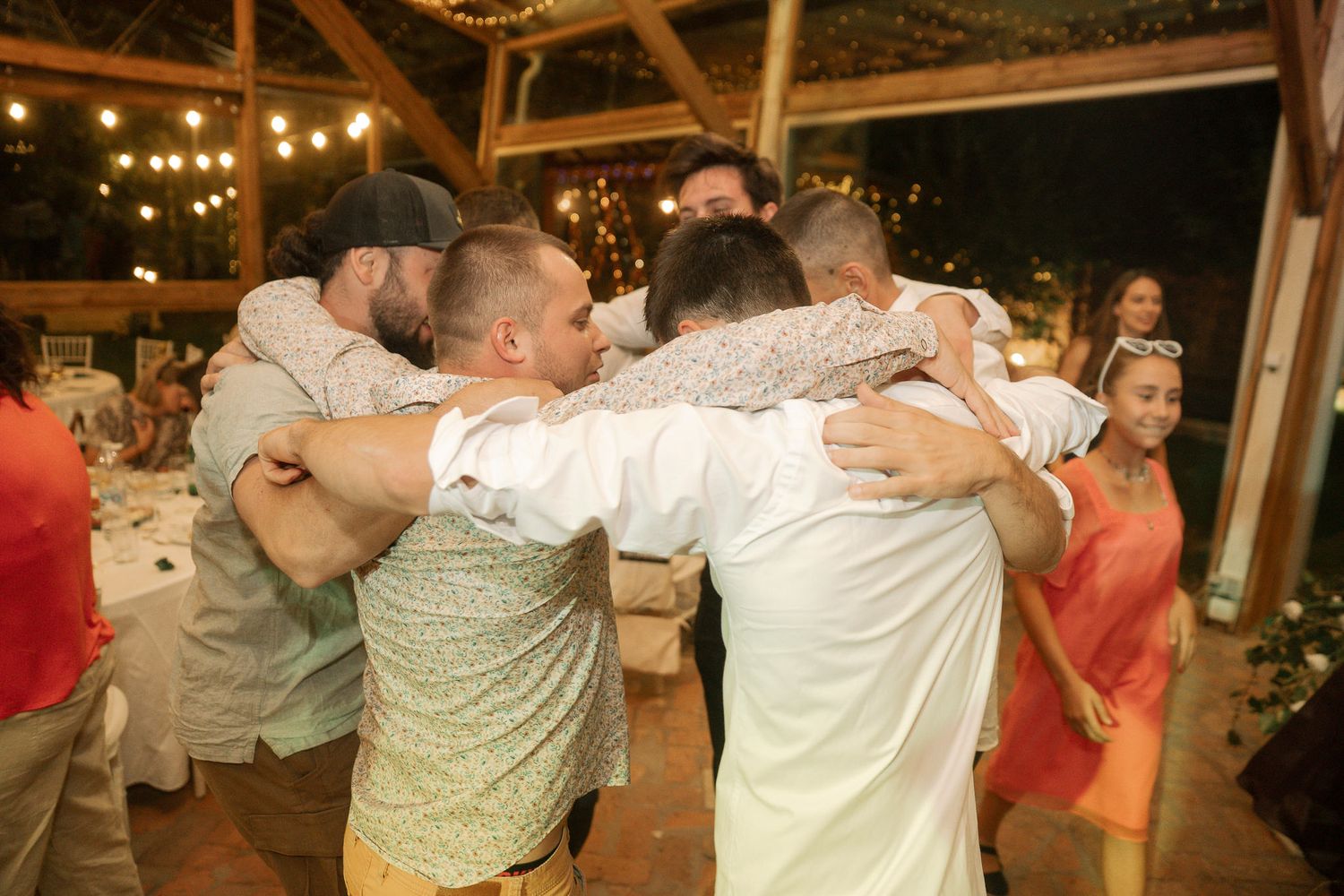 Wedding guests dancing and celebrating together at a rustic barn reception venue with warm lighting.