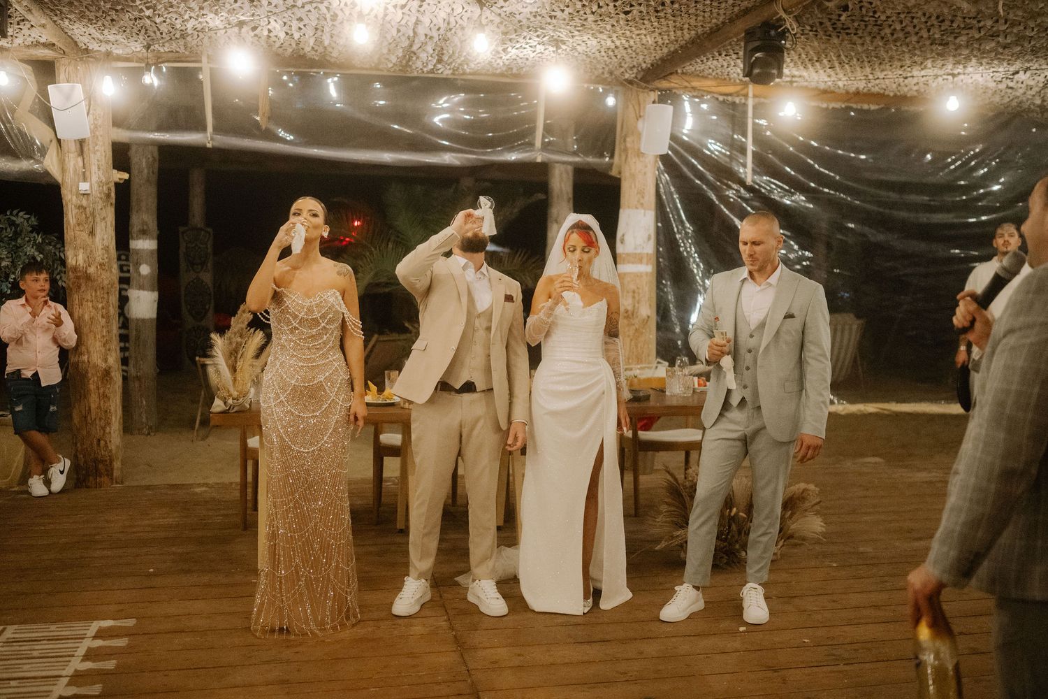 A wedding reception celebration in a rustic barn venue with string lights creating a warm, romantic atmosphere.