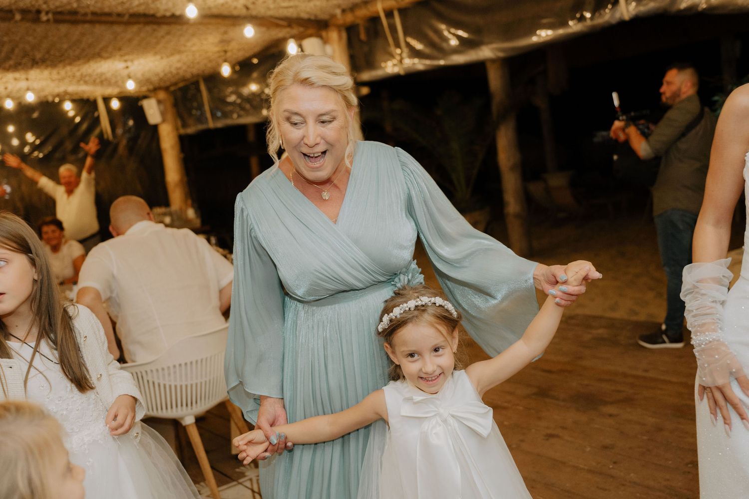 A group of people dance together in a rustic barn venue with warm lighting during a celebration.
