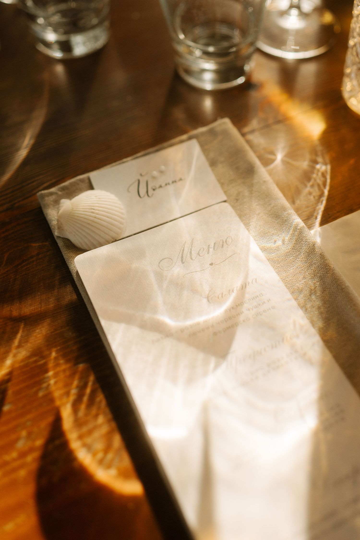 A white napkin on a wooden table with soft lighting and glassware in the background.