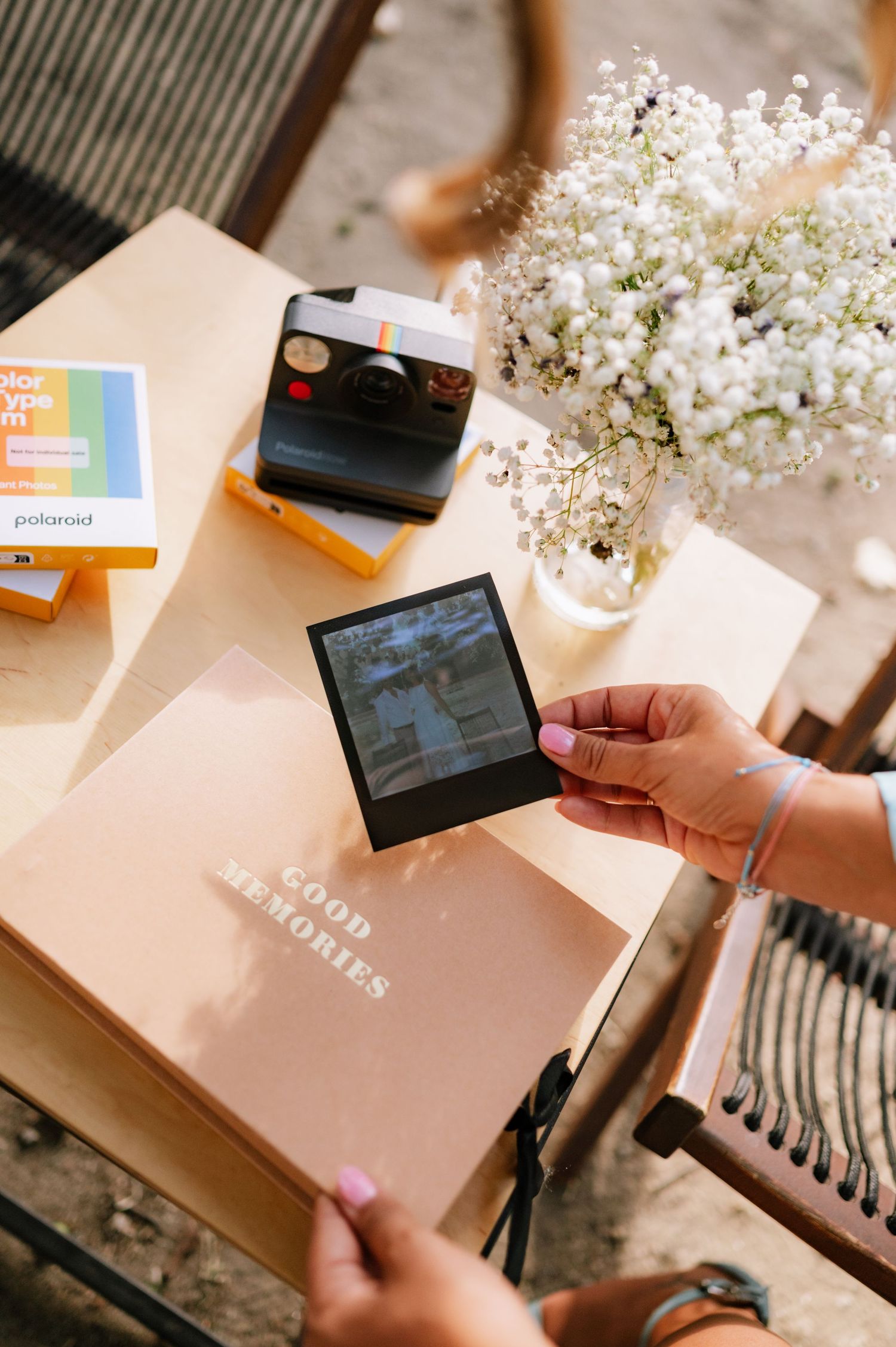 A series of photos showing someone opening a pink package with white flowers and electronic devices on a striped surface.