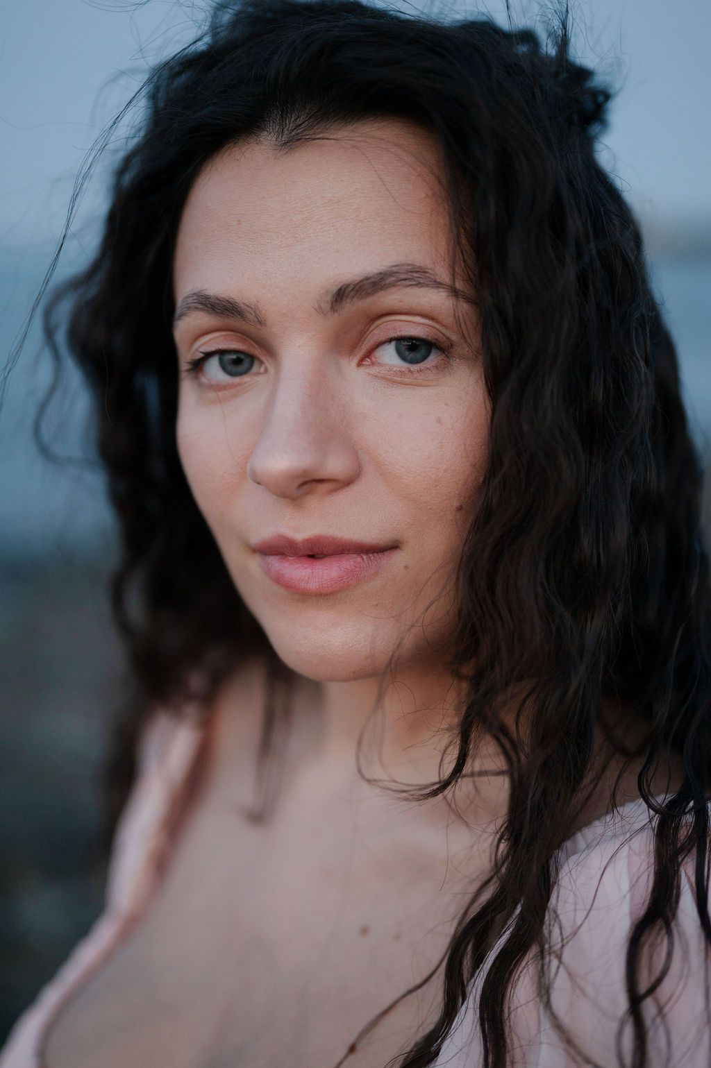 A close-up portrait series showing different angles and expressions with dark windswept hair against a blurred background.