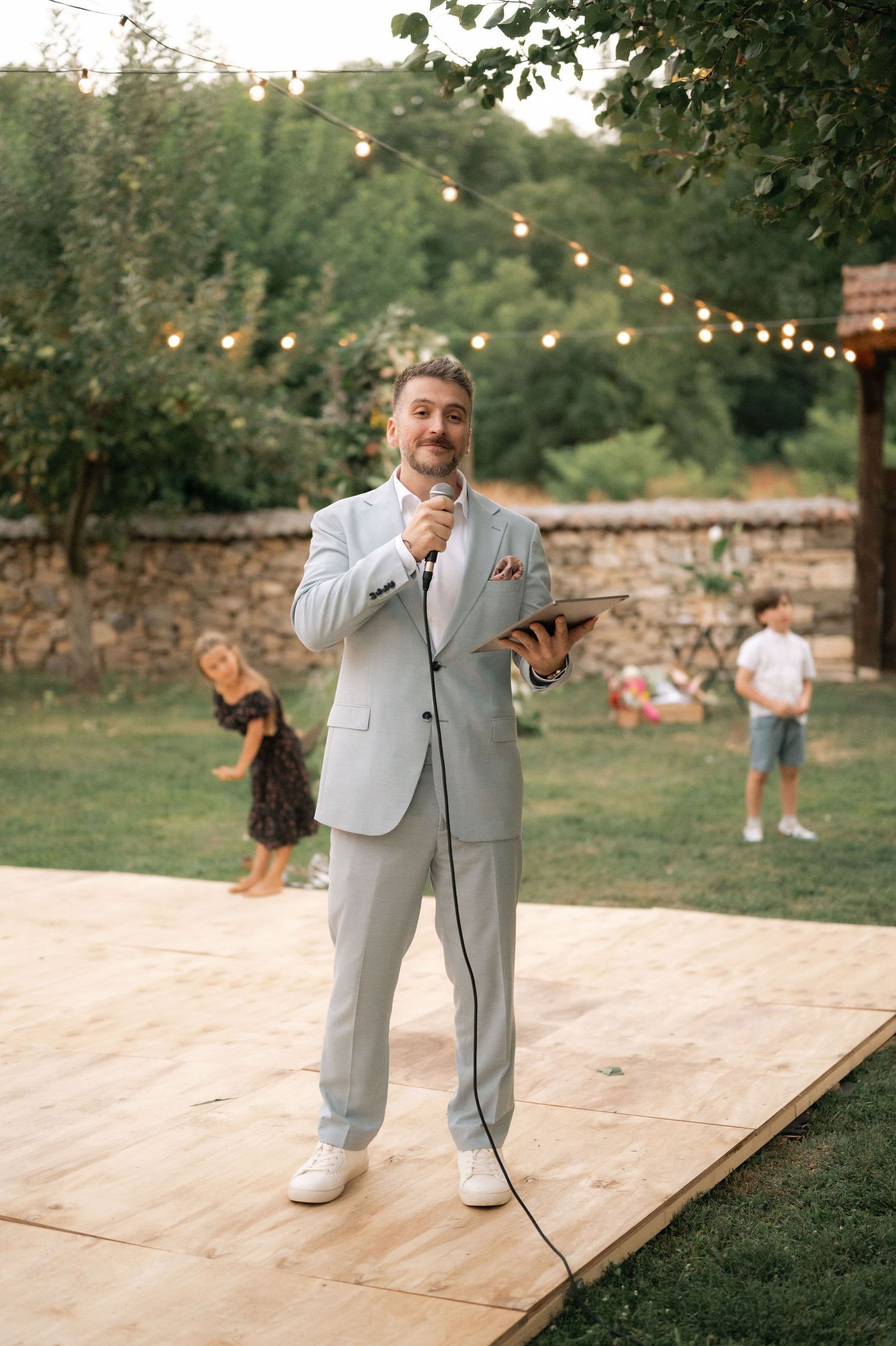 A series of candid moments captured on a wooden dance floor at an outdoor event with string lights overhead.