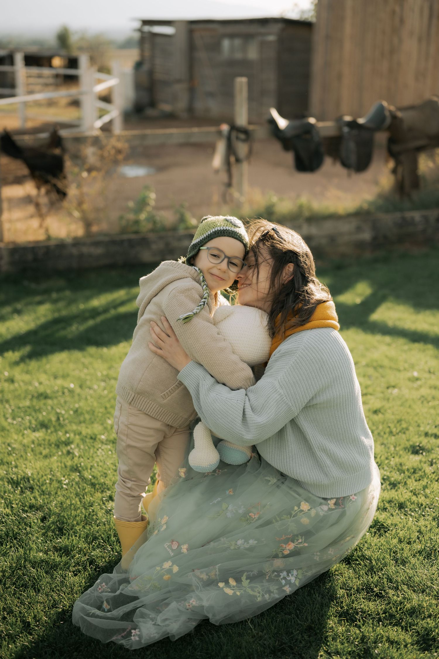 A tender moment captured on a sunny lawn with autumn leaves scattered around.