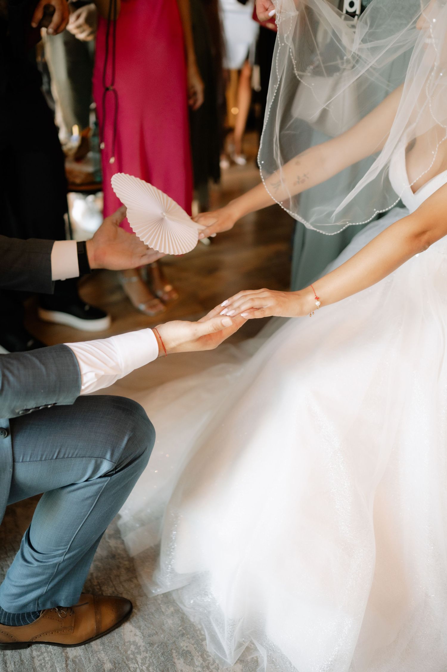 Close-up shots of hands adjusting a white wedding dress and veil during wedding preparations.