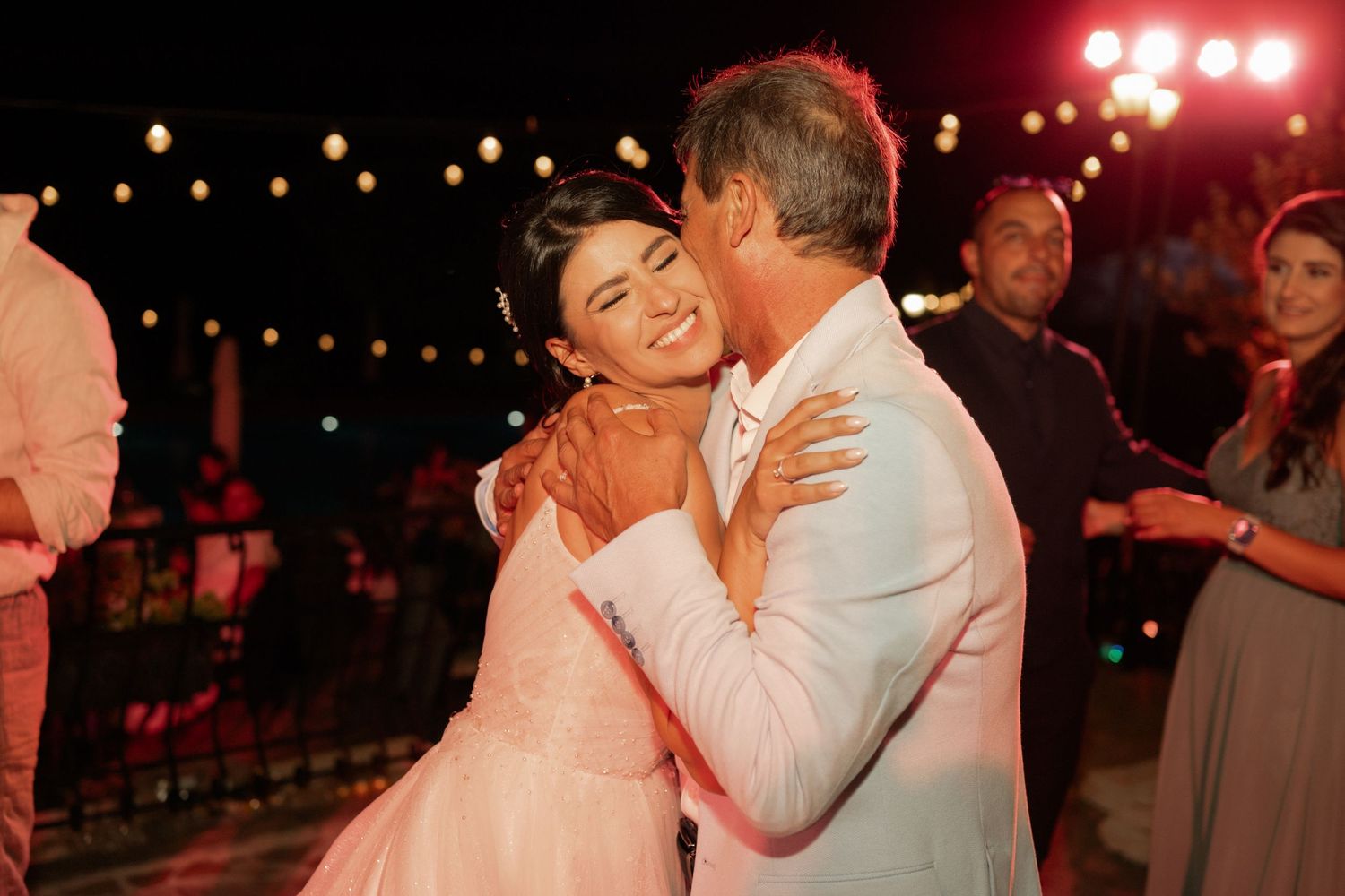 A couple shares a romantic dance moment under warm lighting at an evening celebration.