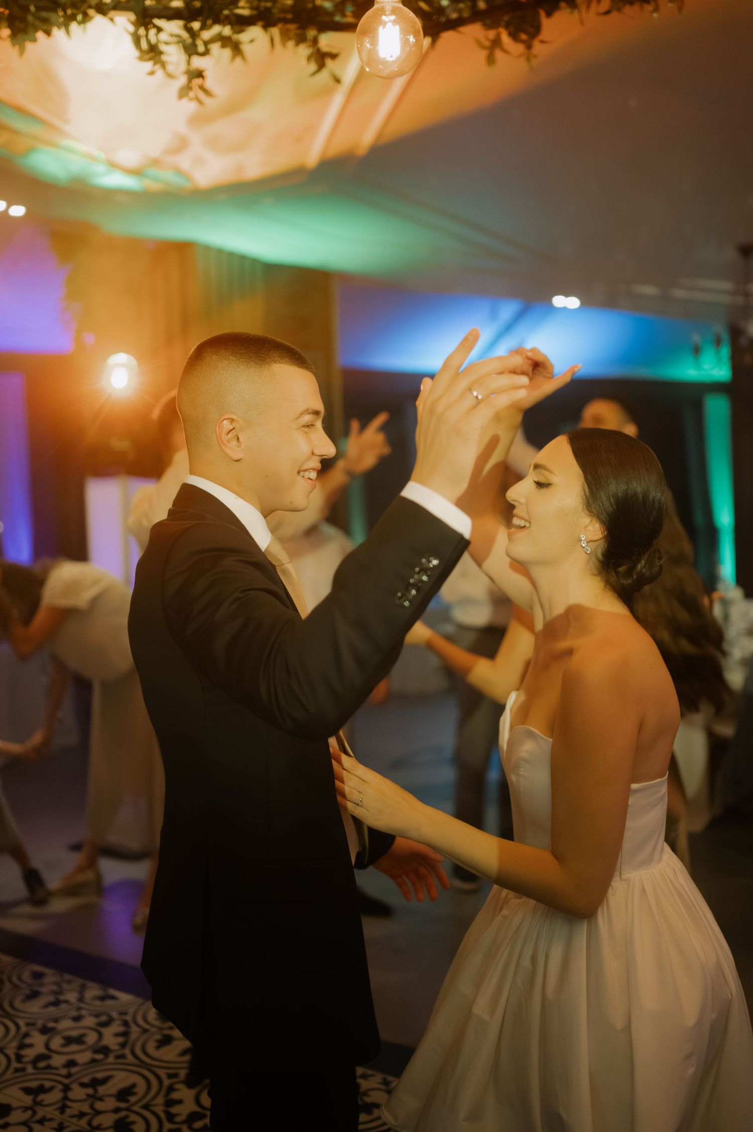 A couple shares a joyful dance moment at their wedding reception under warm lighting and elegant decor.