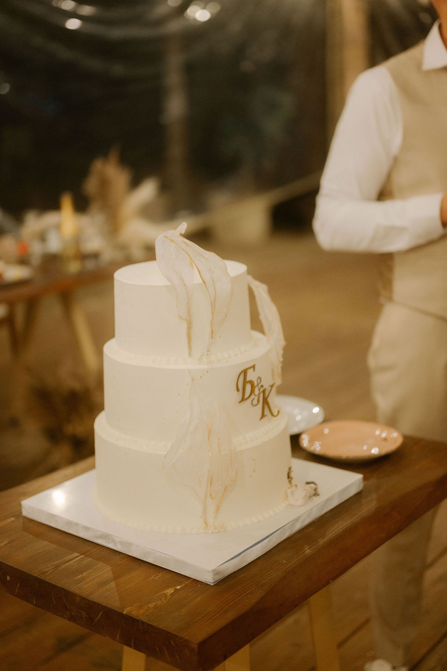 A white wedding cake topper displayed on a wooden surface with soft lighting creating a warm ambiance.