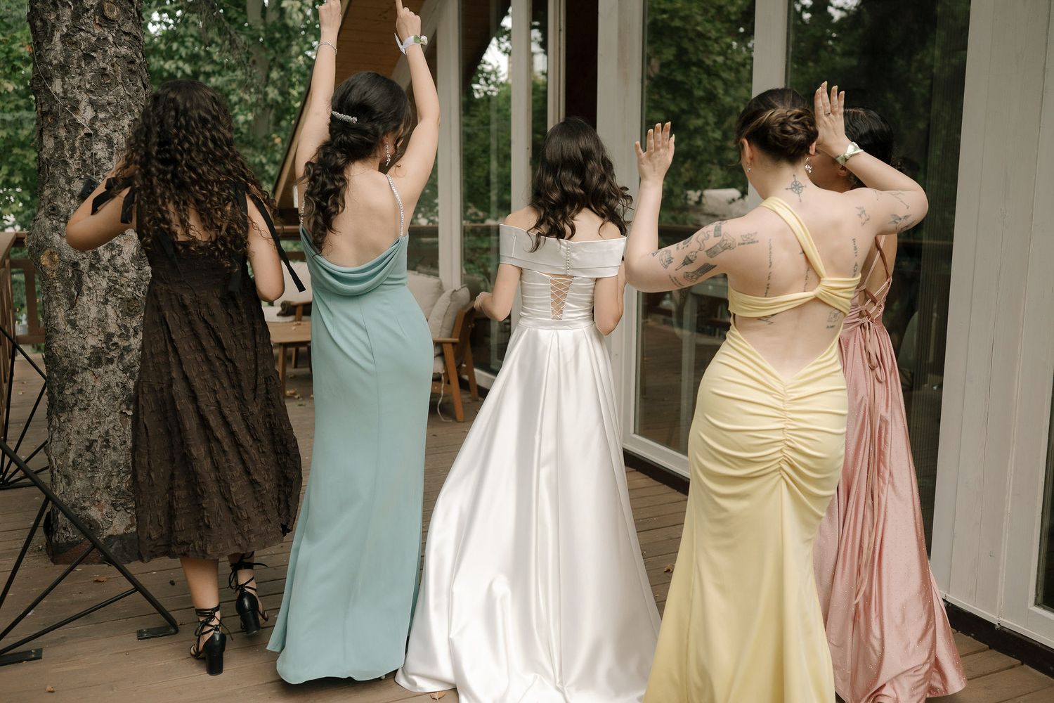A group of bridesmaids in pastel dresses dancing together at a wedding reception.
