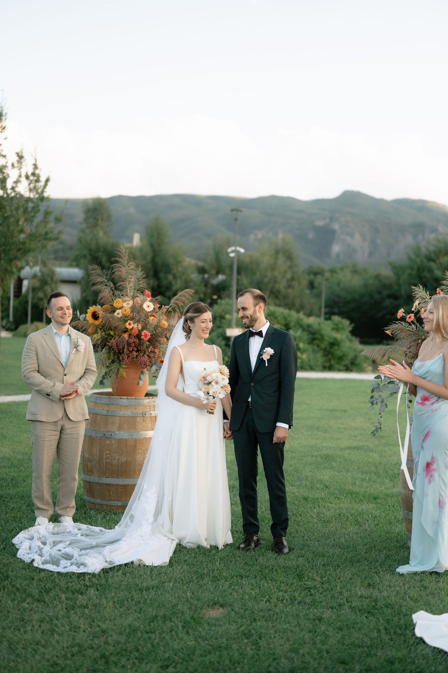 Outdoor wedding ceremony setup with rustic wine barrel decor and floral arrangements against a scenic mountain backdrop.