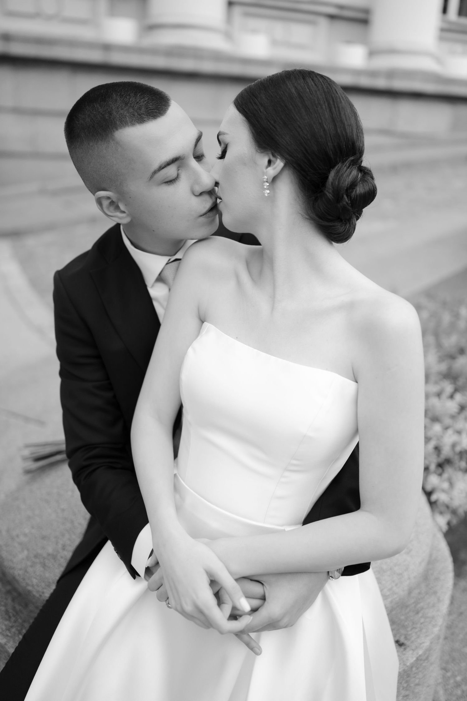 Black and white photo of a bride and groom sharing a kiss, with the bride in a strapless white gown.