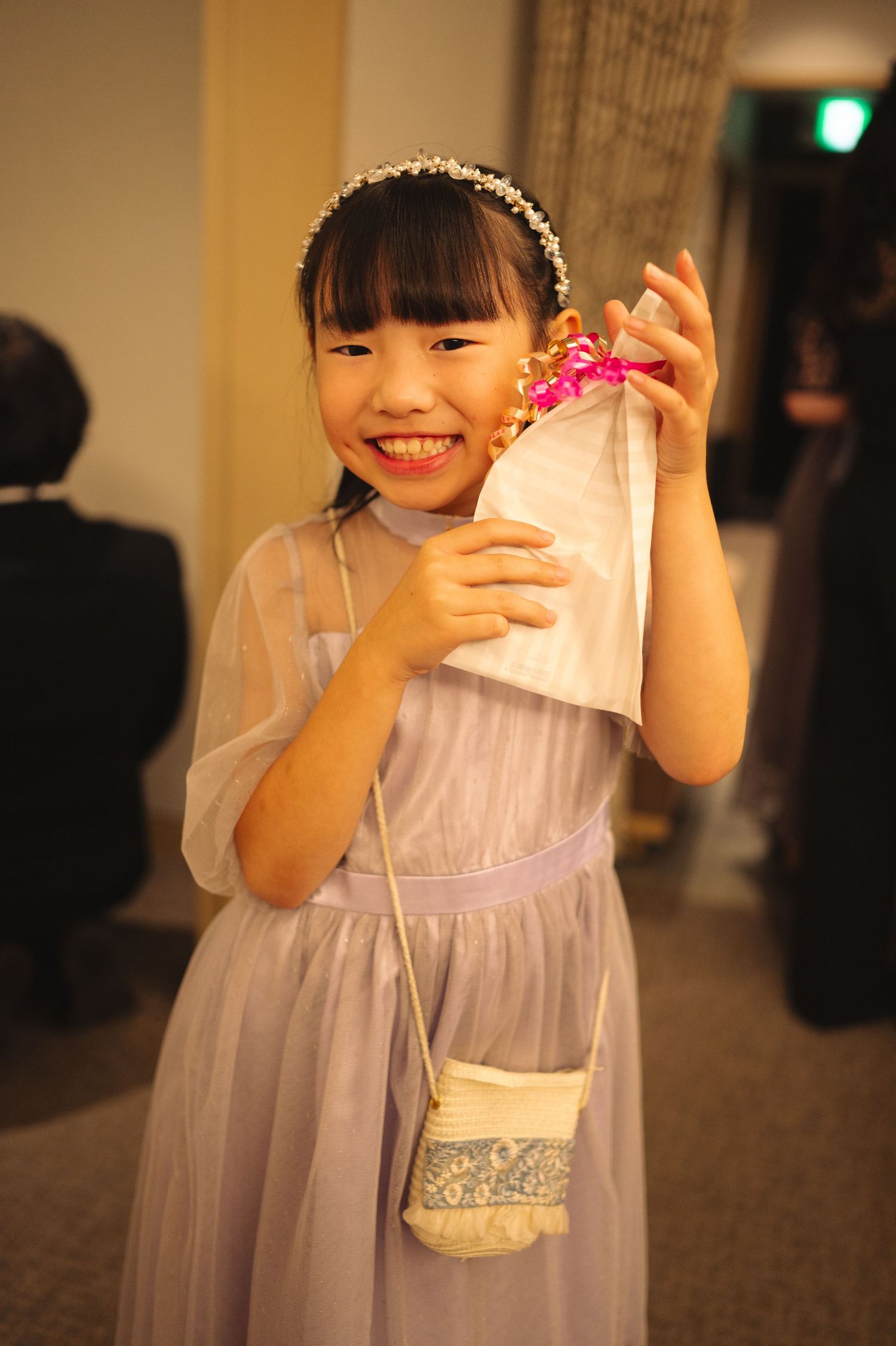 A flower girl in a lavender dress with white details poses at a wedding.