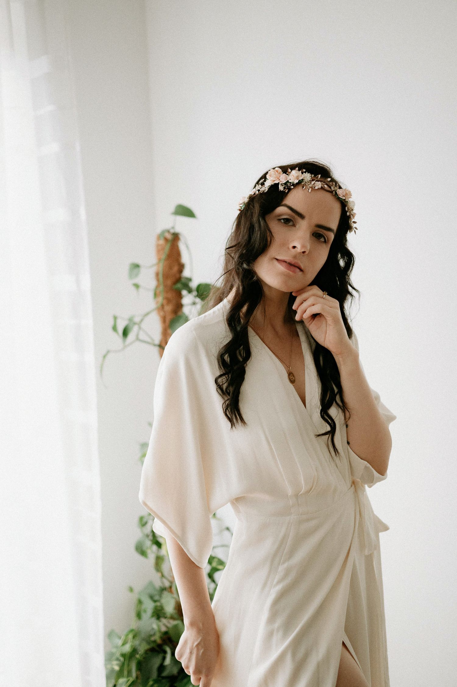 Ethereal portrait featuring soft lighting and floral crown against white minimalist backdrop.
