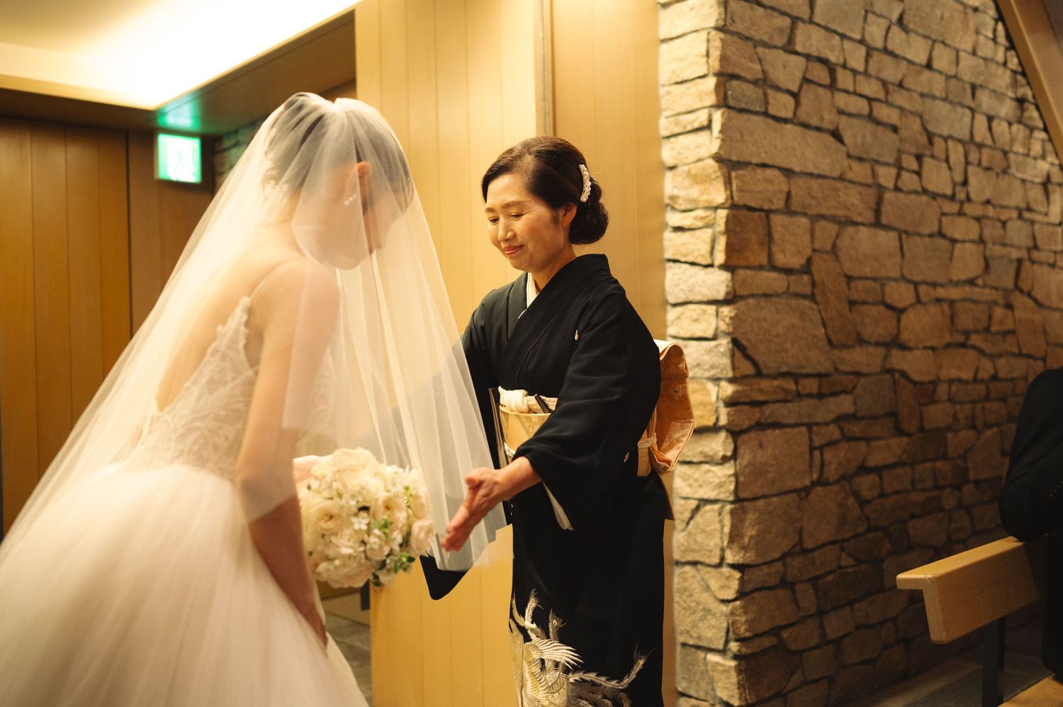 Professional dress fitting showing careful attention to wedding gown and veil arrangement.