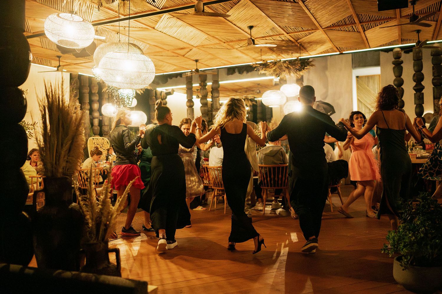 Wedding reception dance party in a rustic venue with exposed wooden ceiling beams.