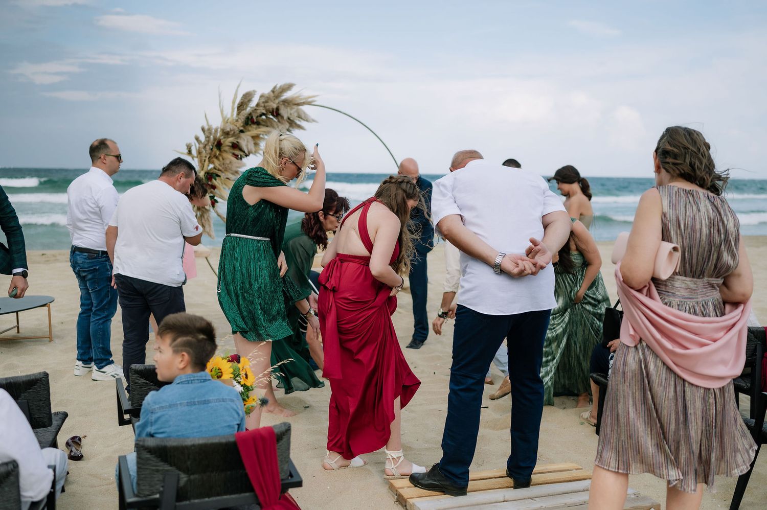 Wedding guests form a line on the beach during an outdoor celebration.