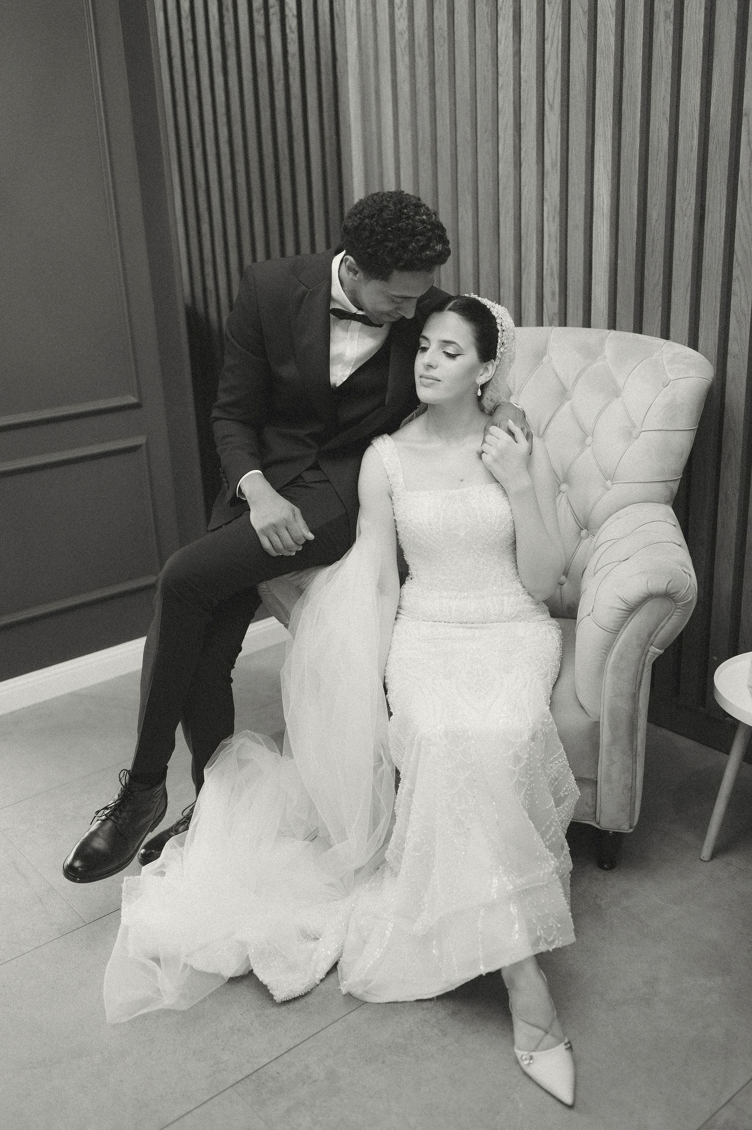 Intimate black and white wedding portraits captured indoors with elegant furniture and lighting.