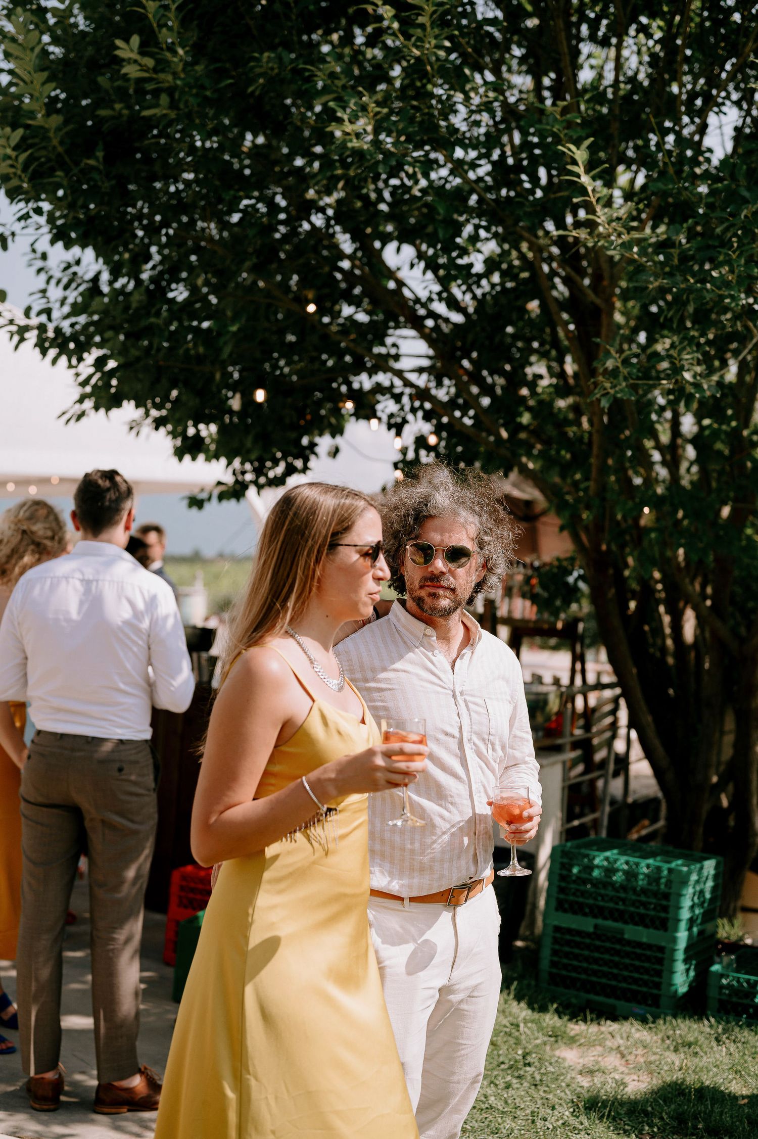 Wedding guests mingling at outdoor reception in summer garden setting.