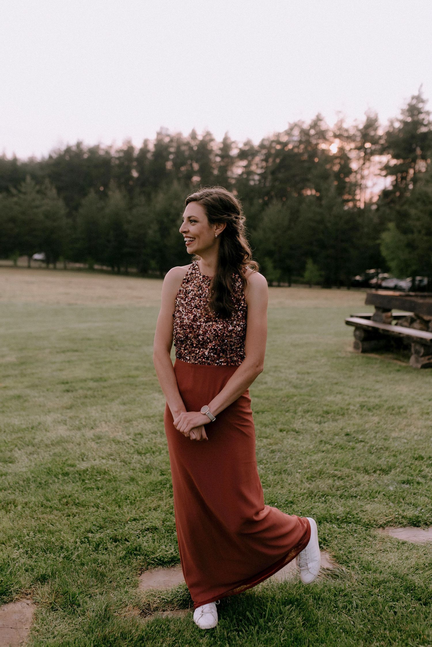 Person in a burgundy dress sitting on grass during golden hour.